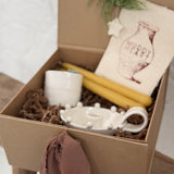Handmade ceramic candle holder with a pair of beeswax candles and a ceramic match striker, arranged as a gift set.