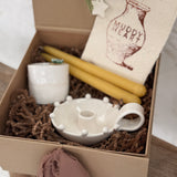 Handmade ceramic candle holder with a pair of beeswax candles and a ceramic match striker, arranged as a gift set.