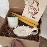 Handmade ceramic candle holder with a pair of beeswax candles and a ceramic match striker, arranged as a gift set.
