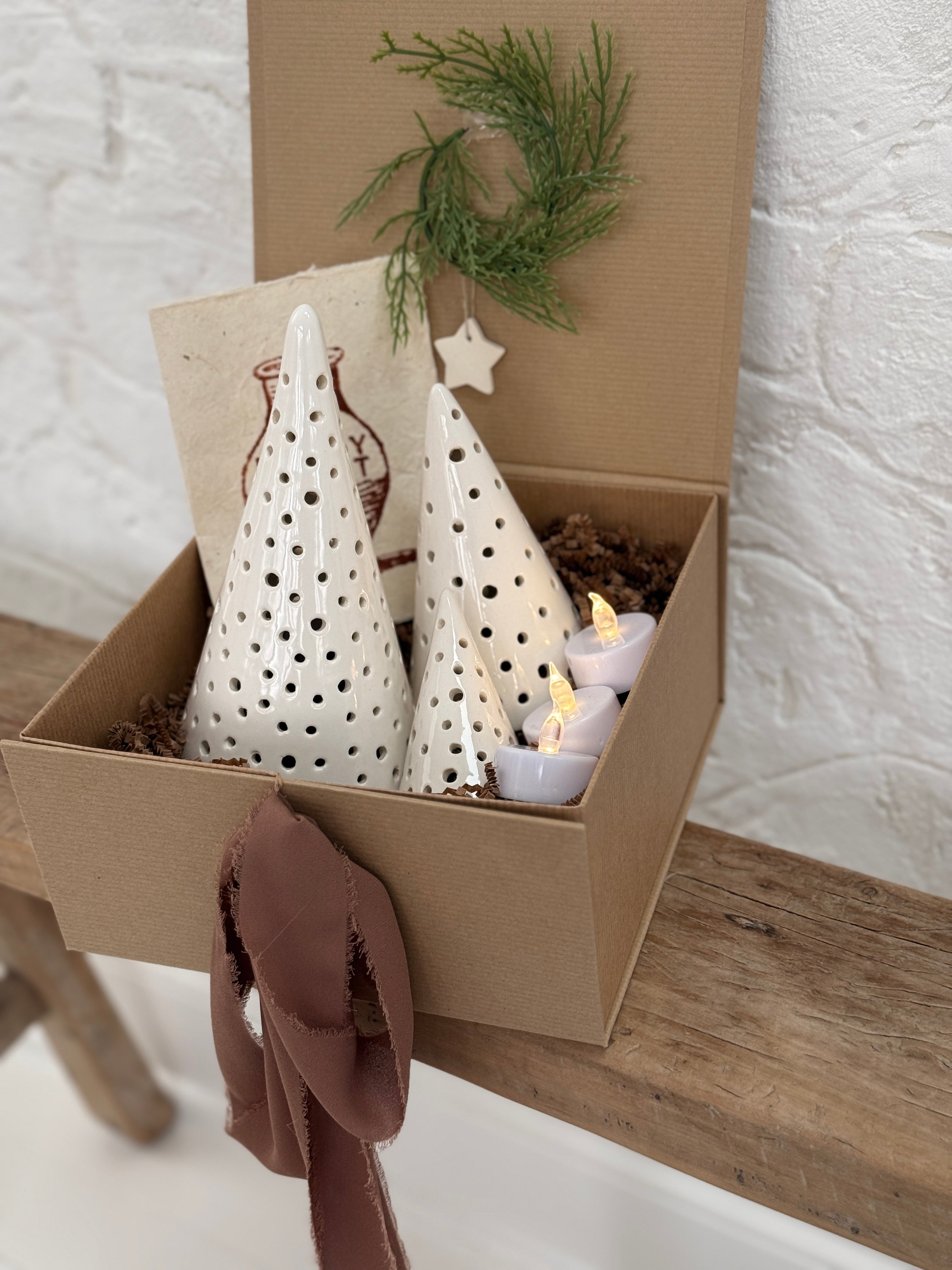 Handmade ceramic luminary tree set glowing with LED tea lights in a ready-to-gift holiday box.