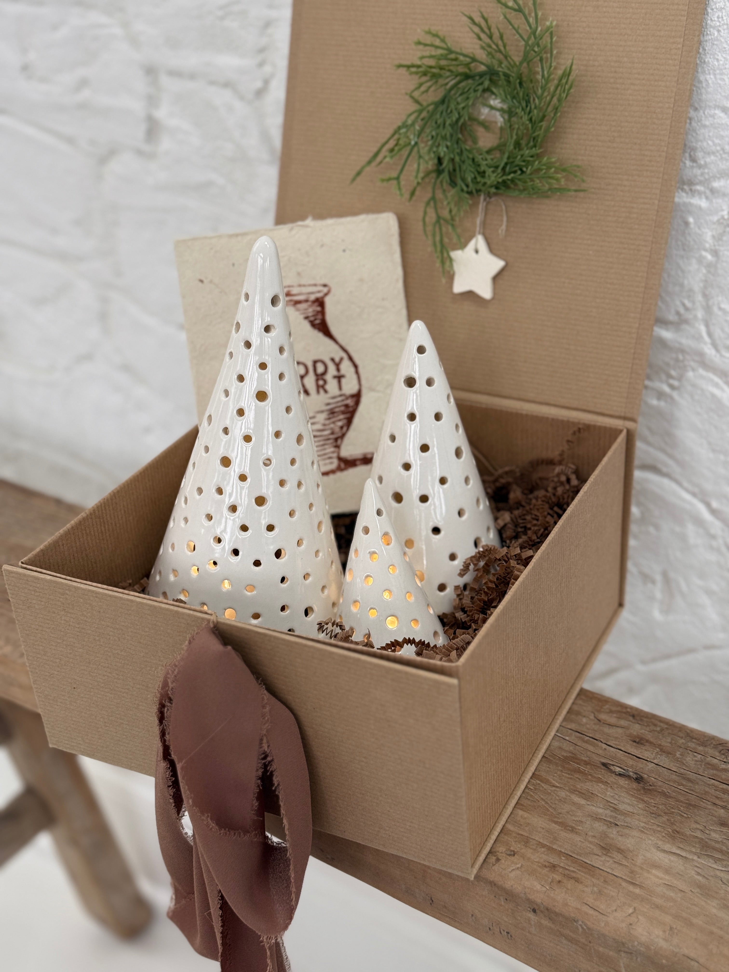 Handmade ceramic luminary tree set glowing with LED tea lights in a ready-to-gift holiday box.