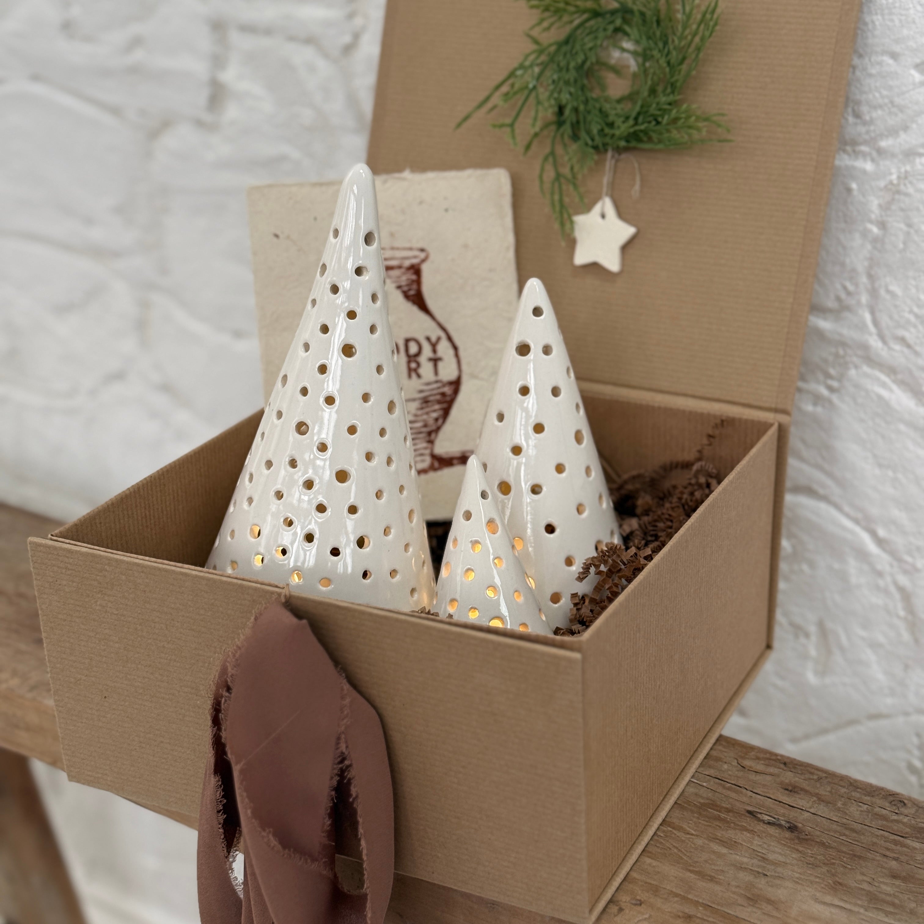 Handmade ceramic luminary tree set glowing with LED tea lights in a ready-to-gift holiday box.