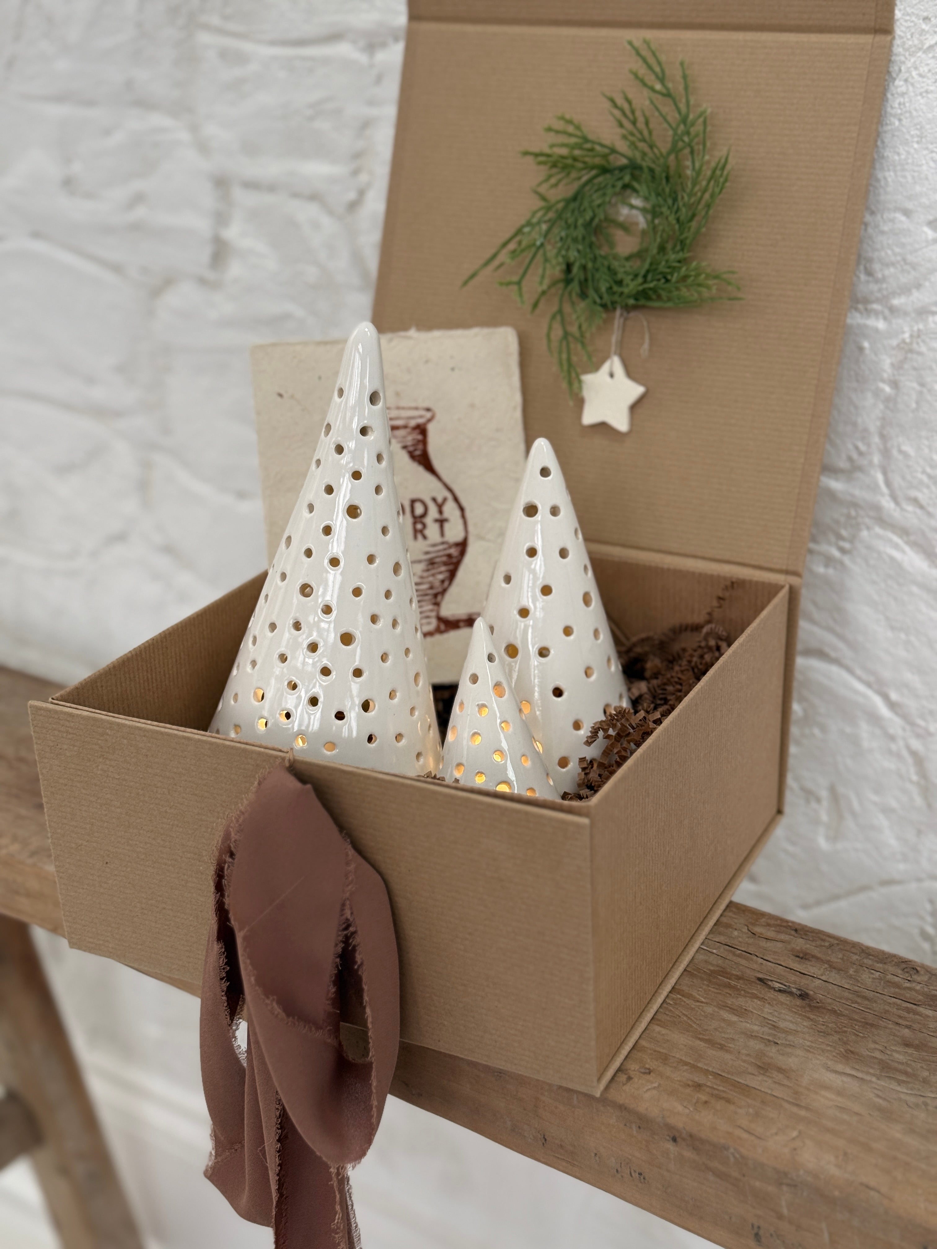 Handmade ceramic luminary tree set glowing with LED tea lights in a ready-to-gift holiday box.