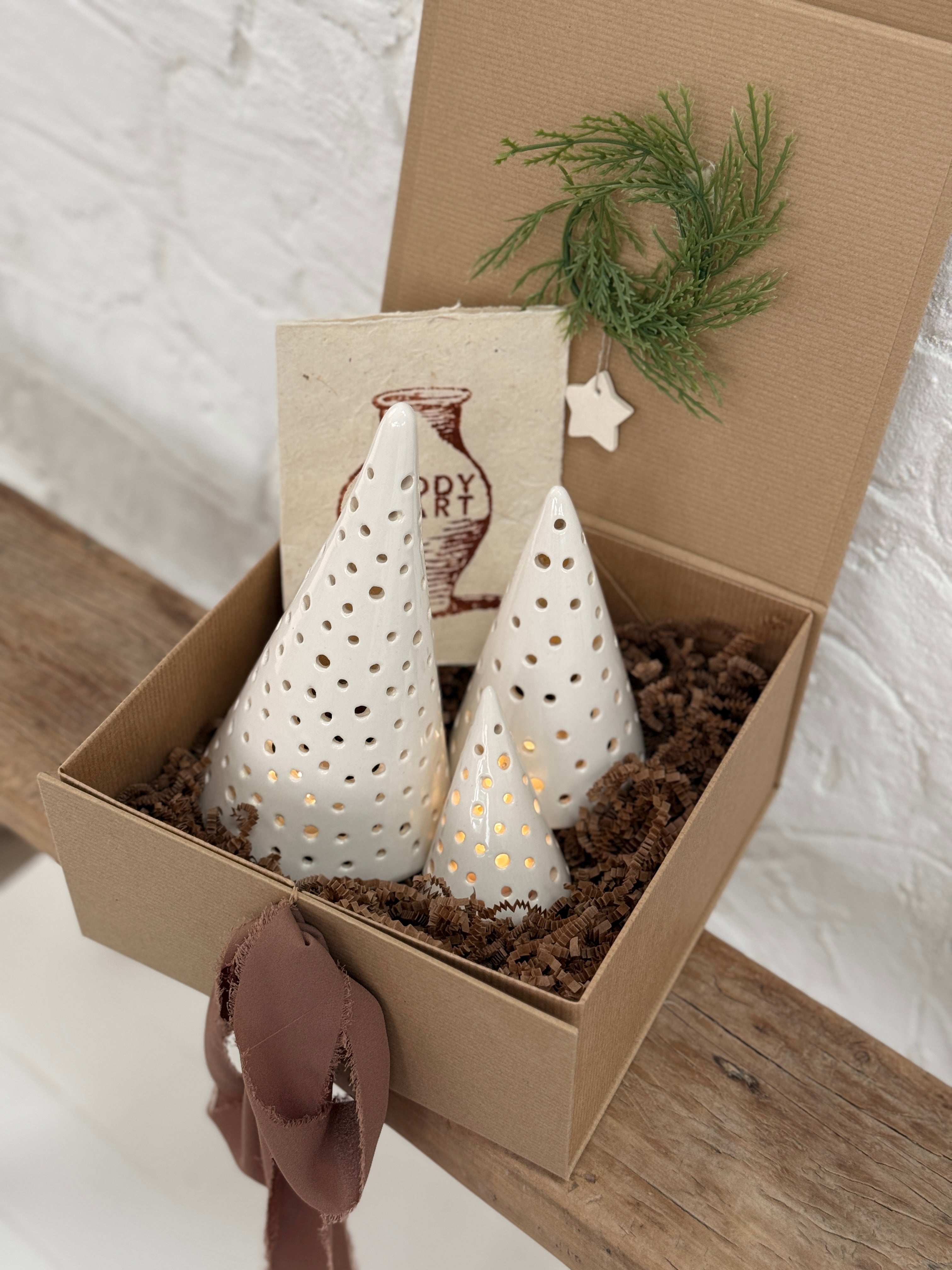 Handmade ceramic luminary tree set glowing with LED tea lights in a ready-to-gift holiday box.