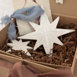 Pair of handmade glossy white ceramic North Star ornaments, one large and one small, tied with ribbon for hanging.
