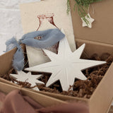 Pair of handmade glossy white ceramic North Star ornaments, one large and one small, tied with ribbon for hanging.