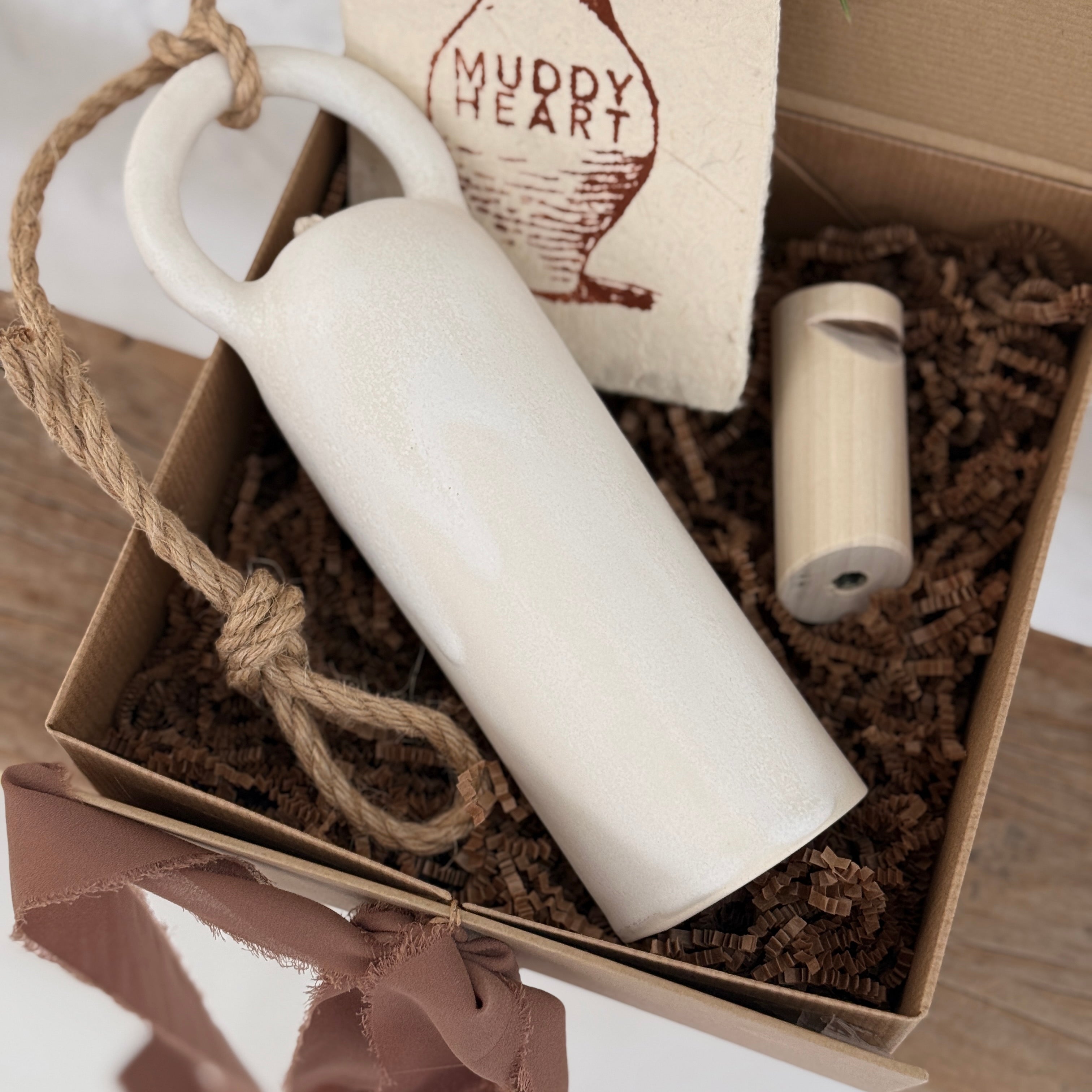 Long handmade ceramic bell in a frost white finish with a solid wood wall peg.