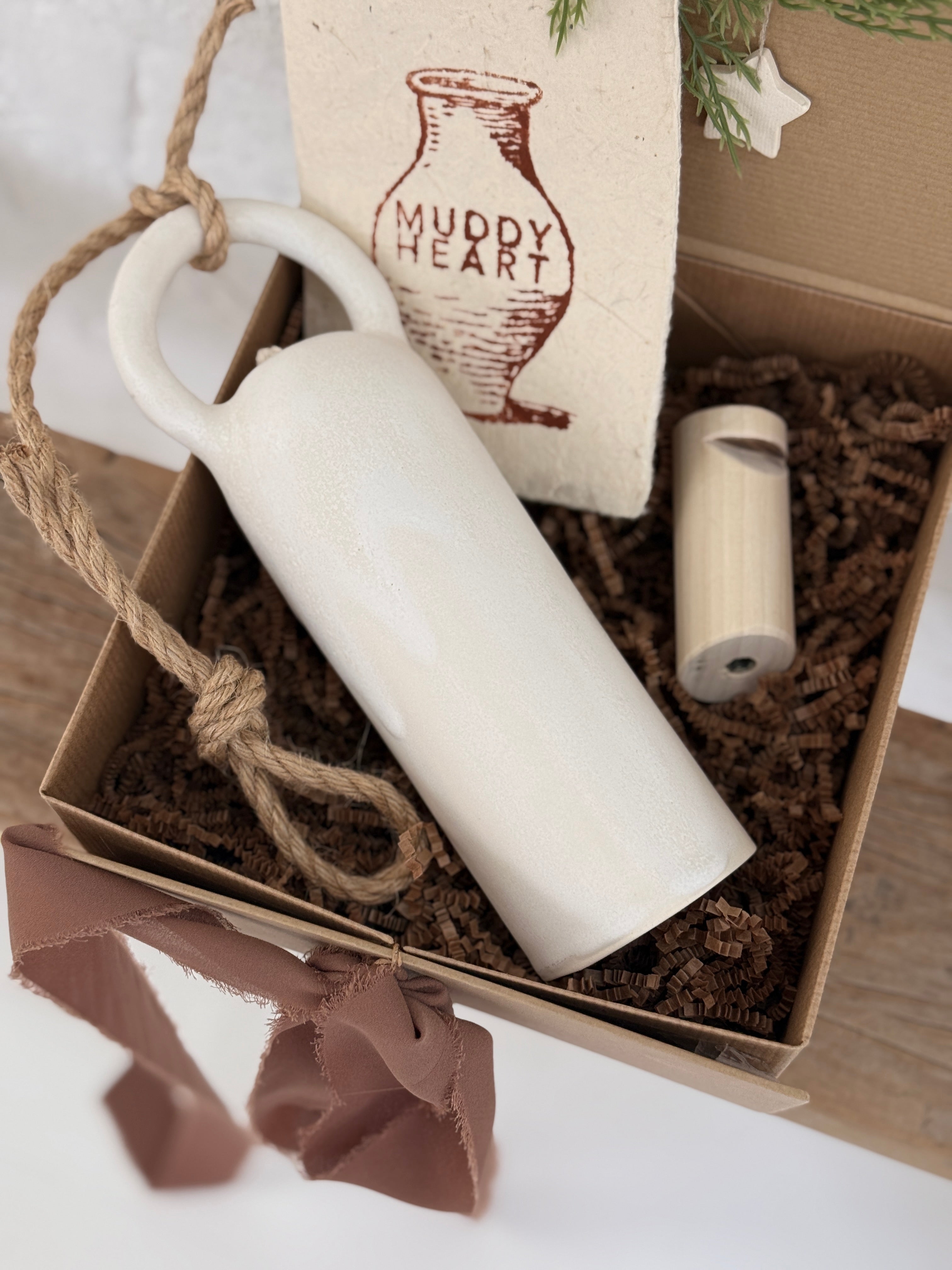 Long handmade ceramic bell in a frost white finish with a solid wood wall peg.