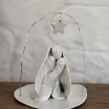 Handmade white ceramic nativity with a delicate star arch, softly sculpted in a minimal modern form.