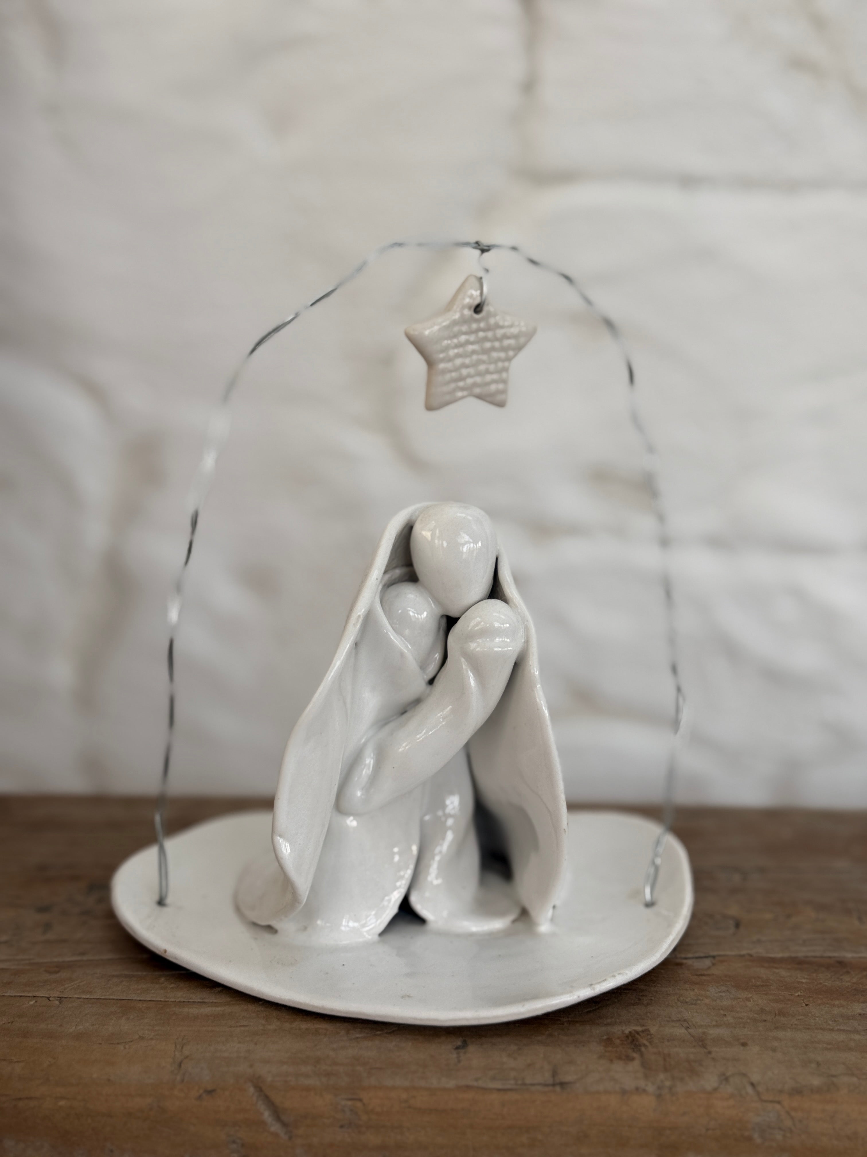 Handmade white ceramic nativity with a delicate star arch, softly sculpted in a minimal modern form.
