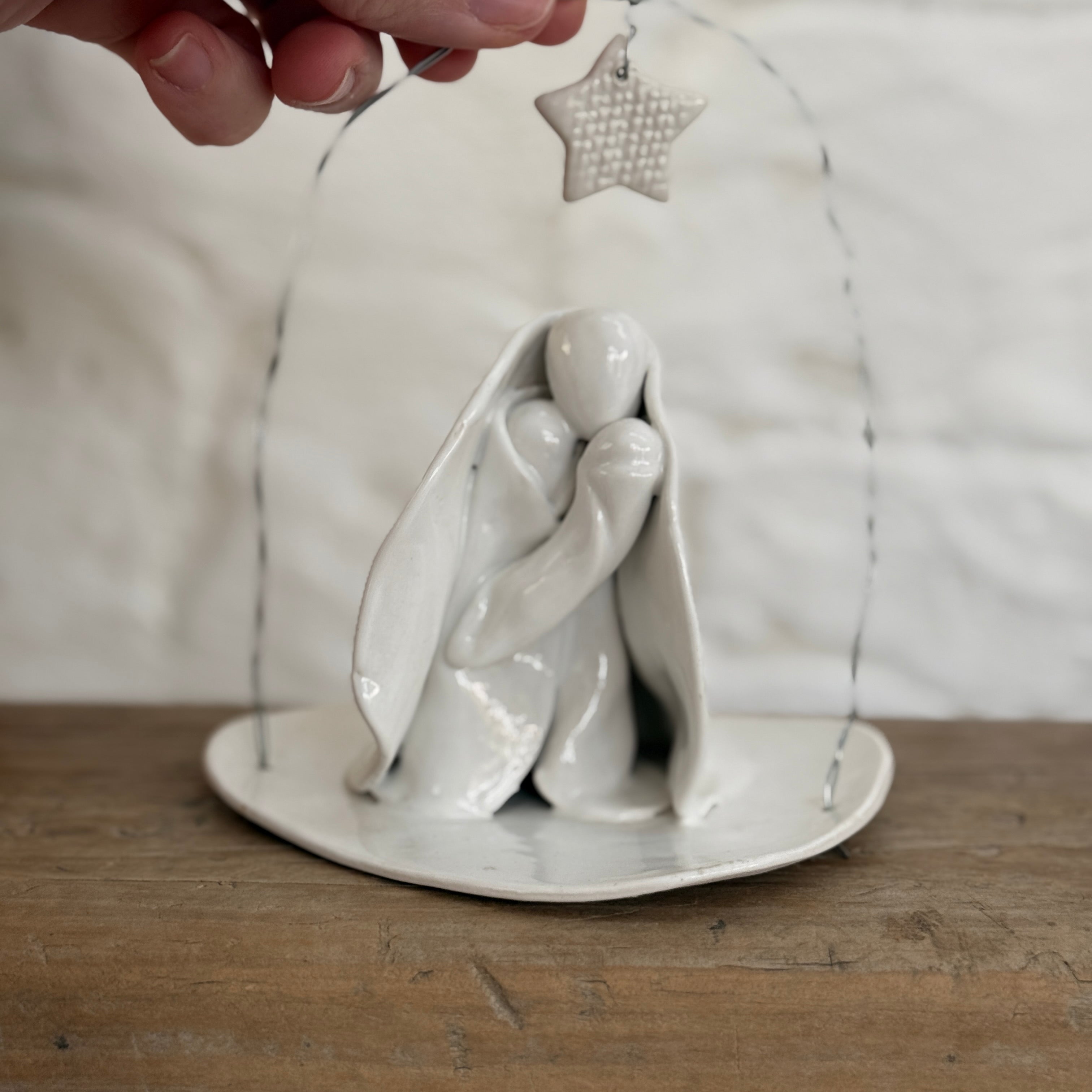 Handmade white ceramic nativity with a delicate star arch, softly sculpted in a minimal modern form.