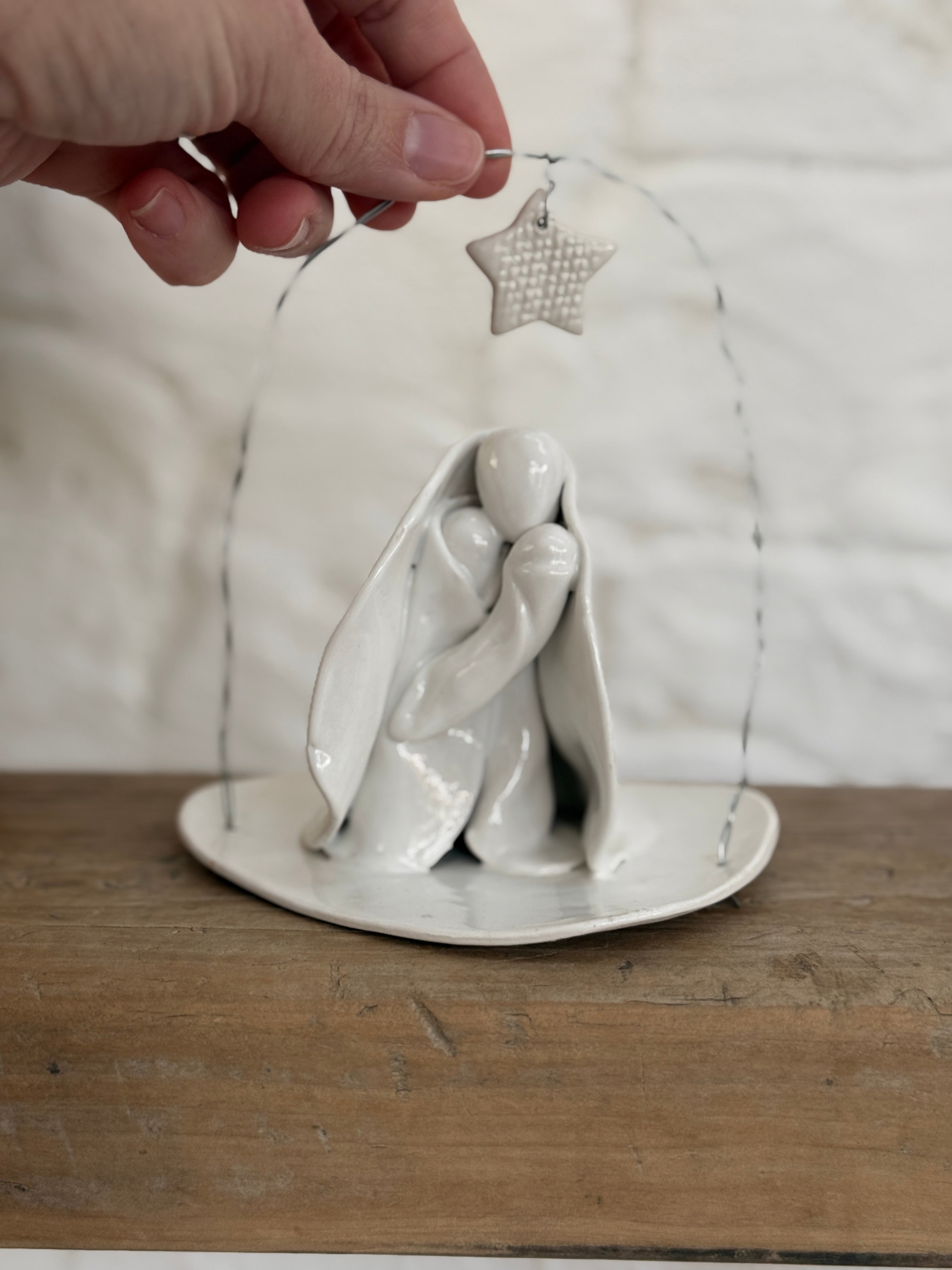 Handmade white ceramic nativity with a delicate star arch, softly sculpted in a minimal modern form.