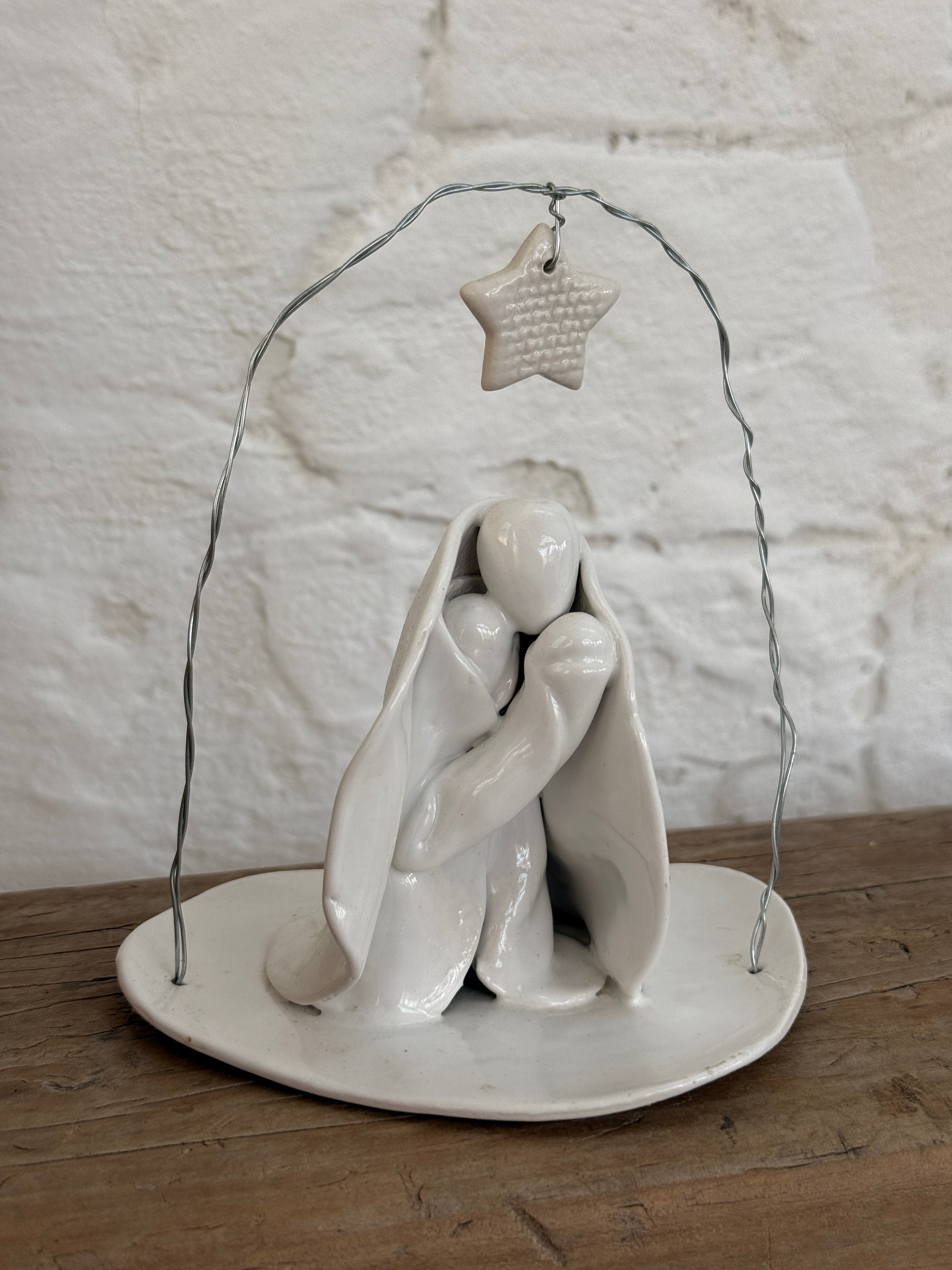Handmade white ceramic nativity with a delicate star arch, softly sculpted in a minimal modern form.