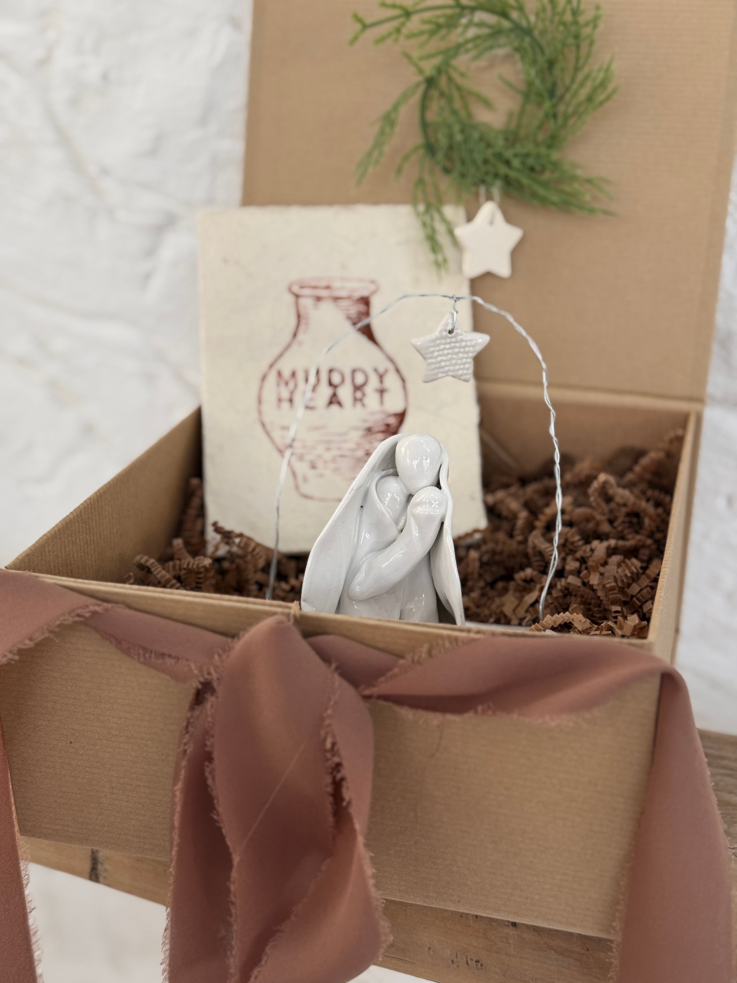Handmade white ceramic nativity with a delicate star arch, softly sculpted in a minimal modern form.