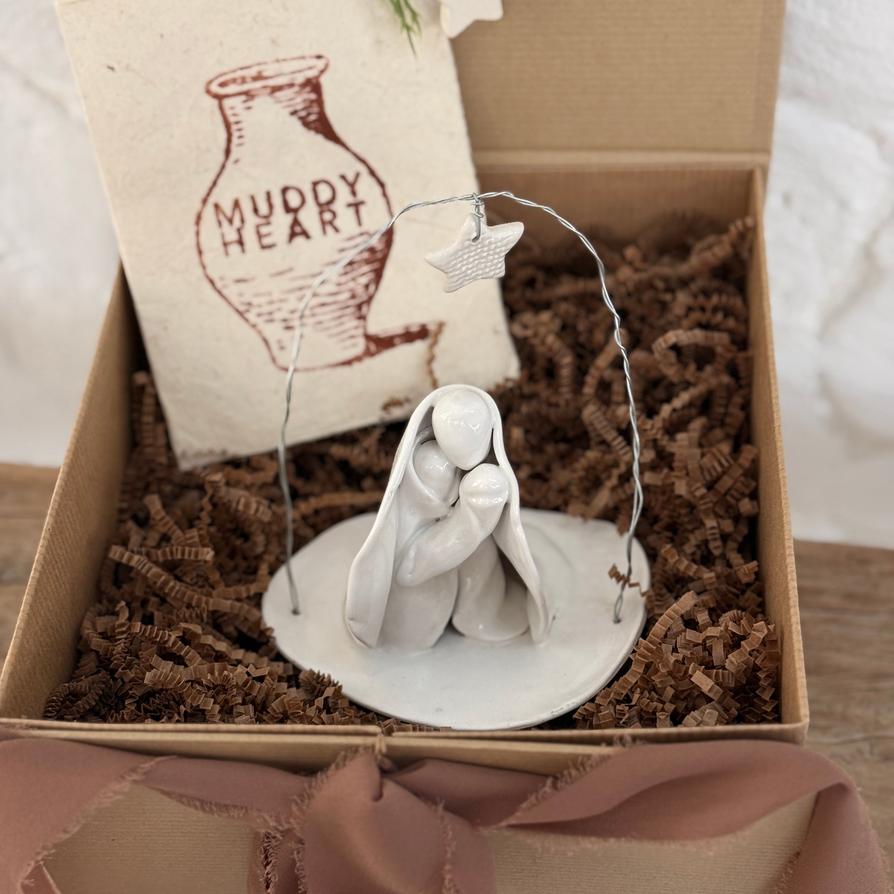 Handmade white ceramic nativity with a delicate star arch, softly sculpted in a minimal modern form.