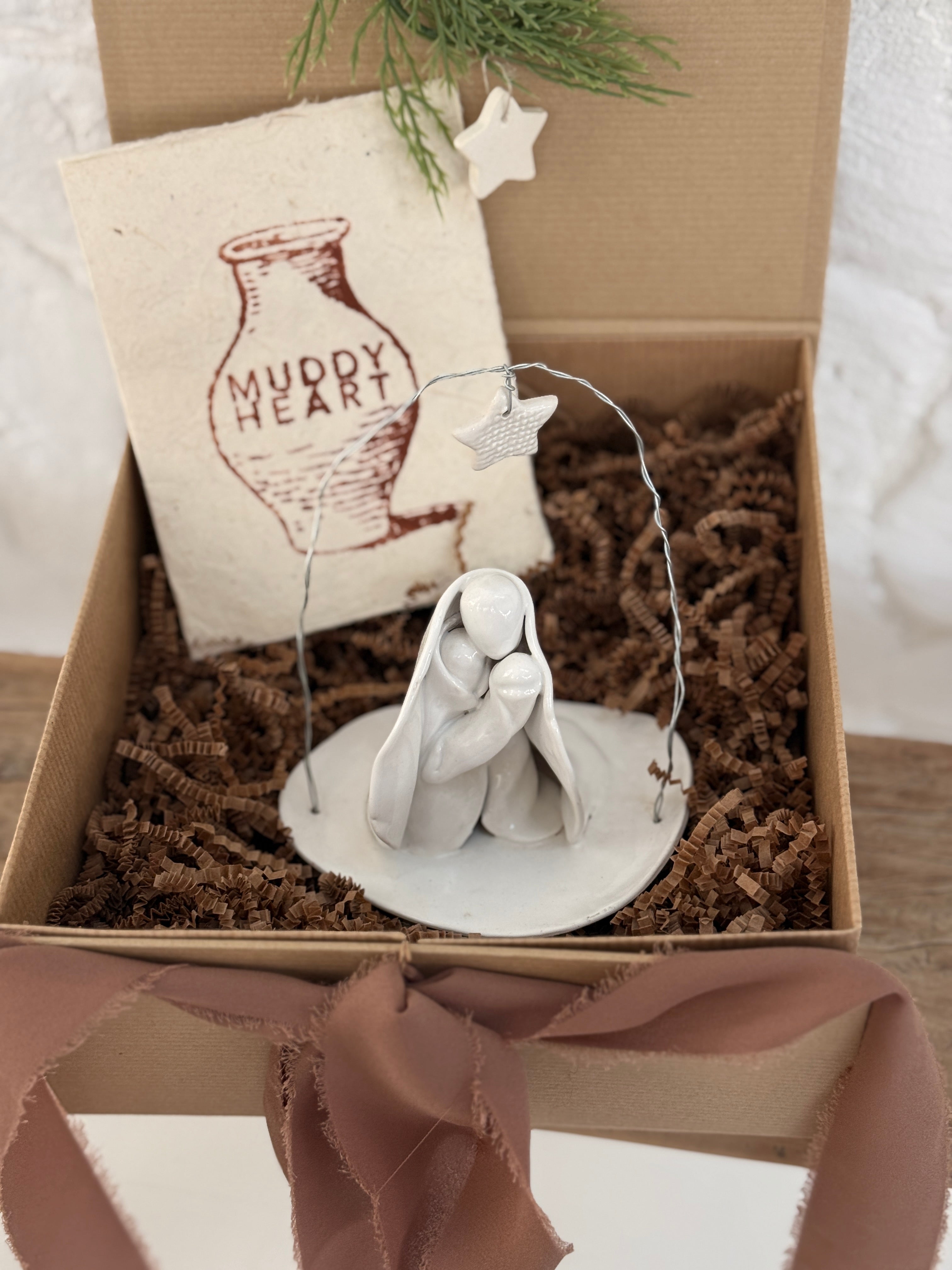 Handmade white ceramic nativity with a delicate star arch, softly sculpted in a minimal modern form.
