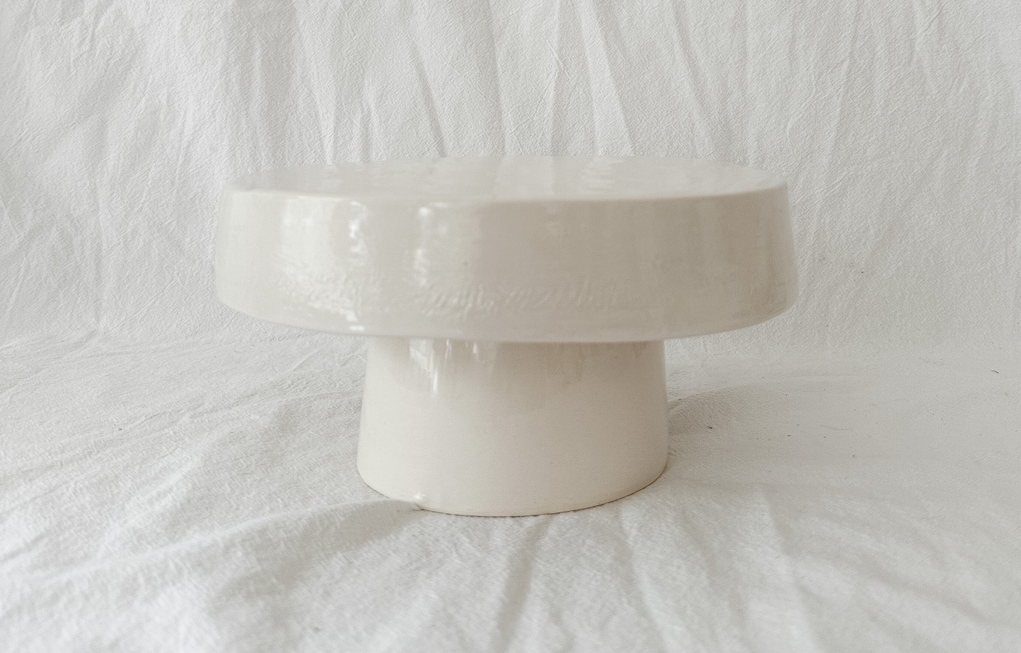 Handmade white ceramic cake stand with a delicate lace-textured plate in glossy white glaze, made to order by Muddy Heart