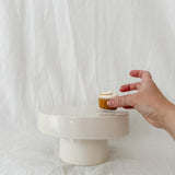 Handmade white ceramic cake stand with a delicate lace-textured plate in glossy white glaze, made to order by Muddy Heart