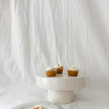 Handmade white ceramic cake stand with a delicate lace-textured plate in glossy white glaze, made to order by Muddy Heart