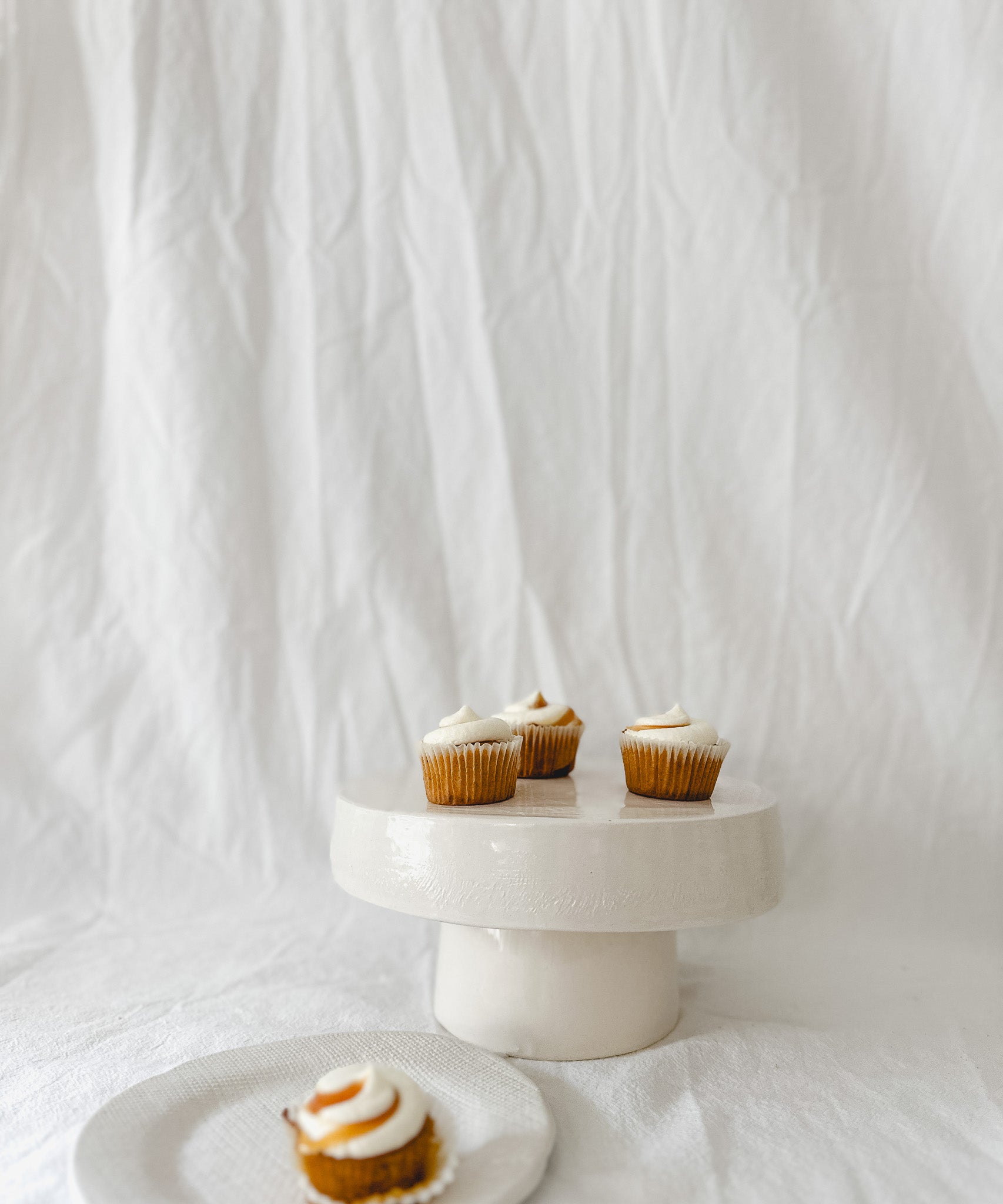 Handmade white ceramic cake stand with a delicate lace-textured plate in glossy white glaze, made to order by Muddy Heart