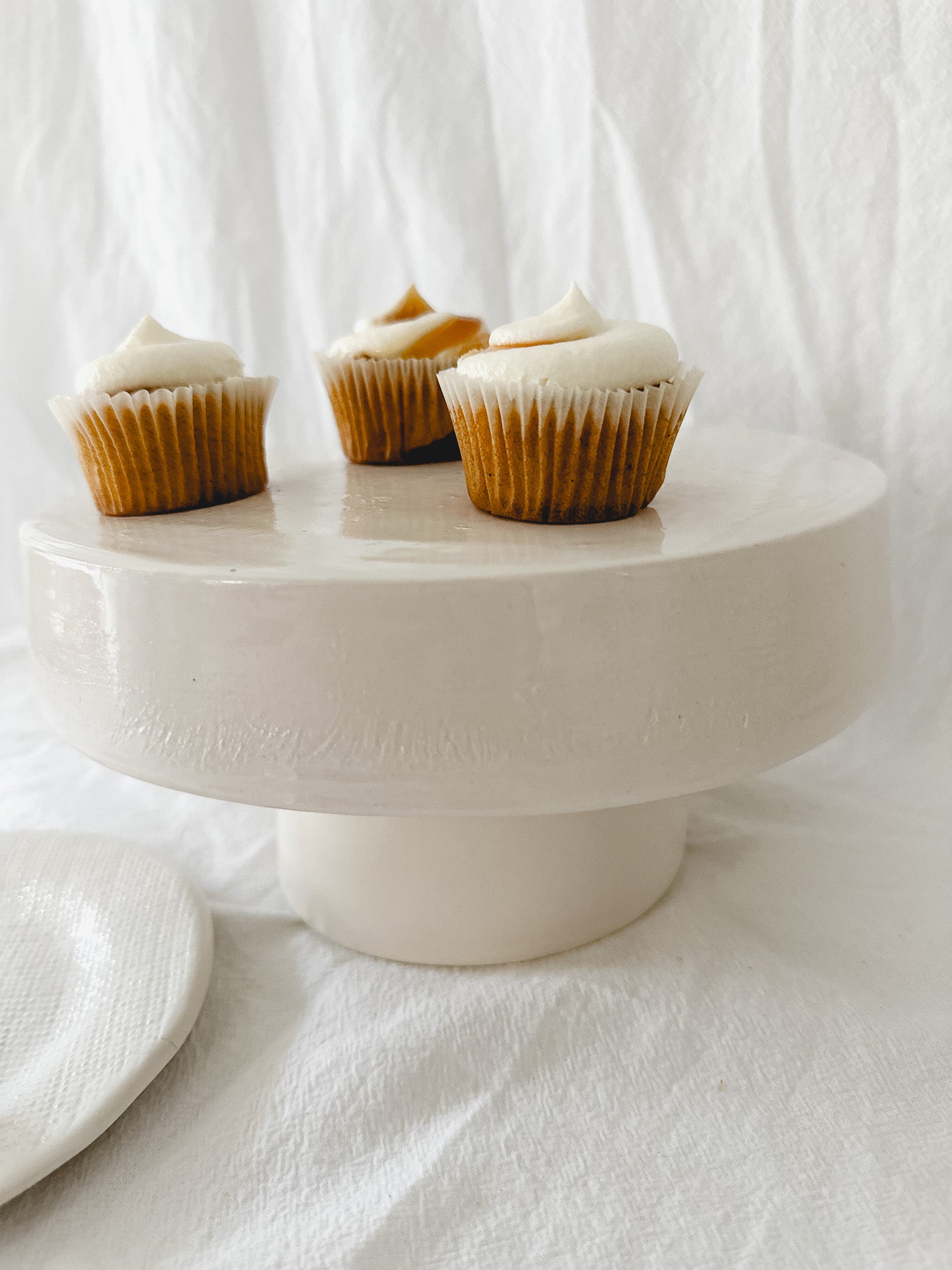 Handmade white ceramic cake stand with a delicate lace-textured plate in glossy white glaze, made to order by Muddy Heart