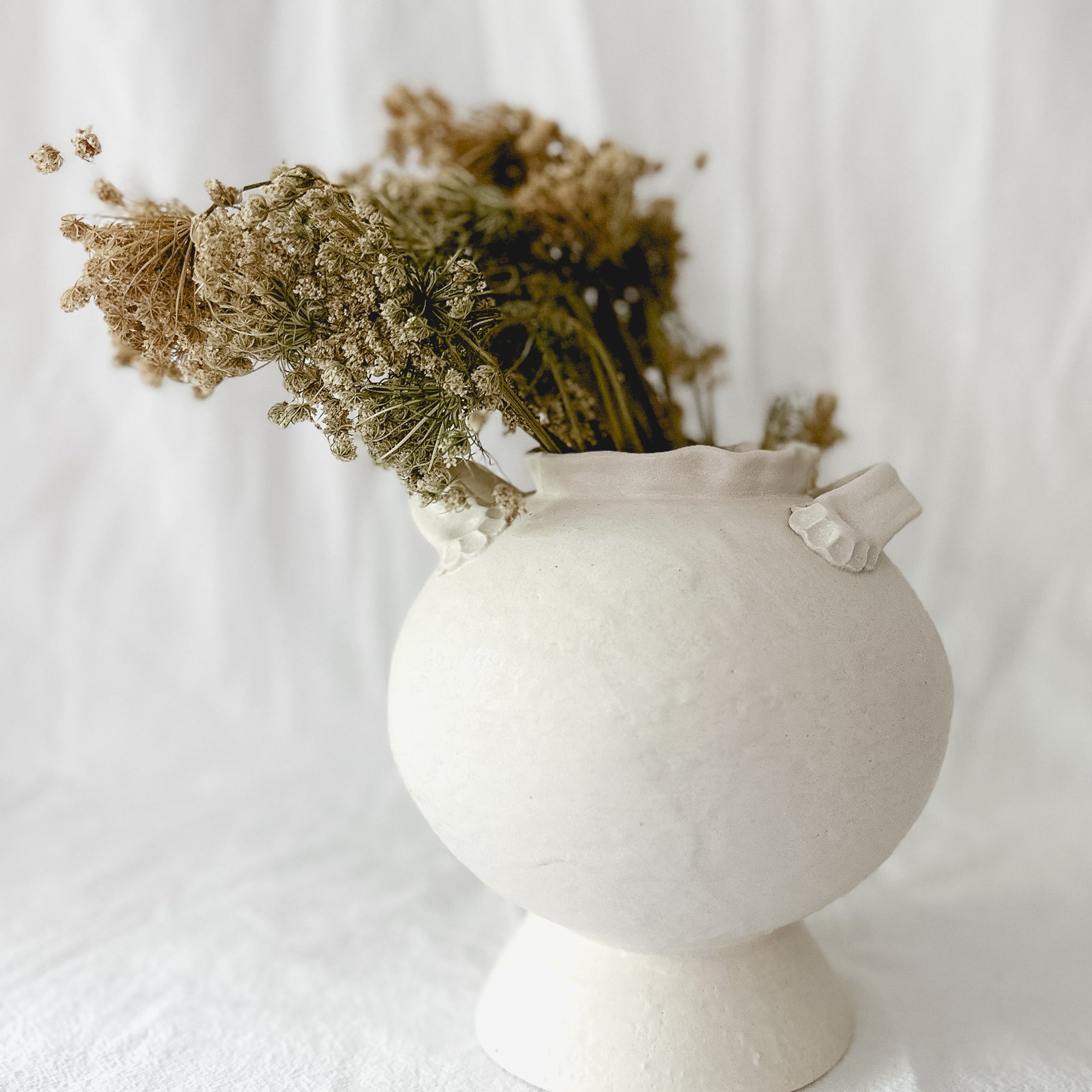 Handmade footed ceramic vase in frost-white glaze with a rounded bellied silhouette, 7 inches wide