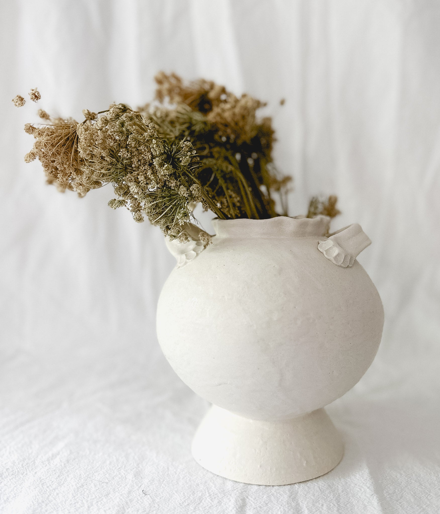Handmade bellied ceramic vase on a footed base, frost-white glaze