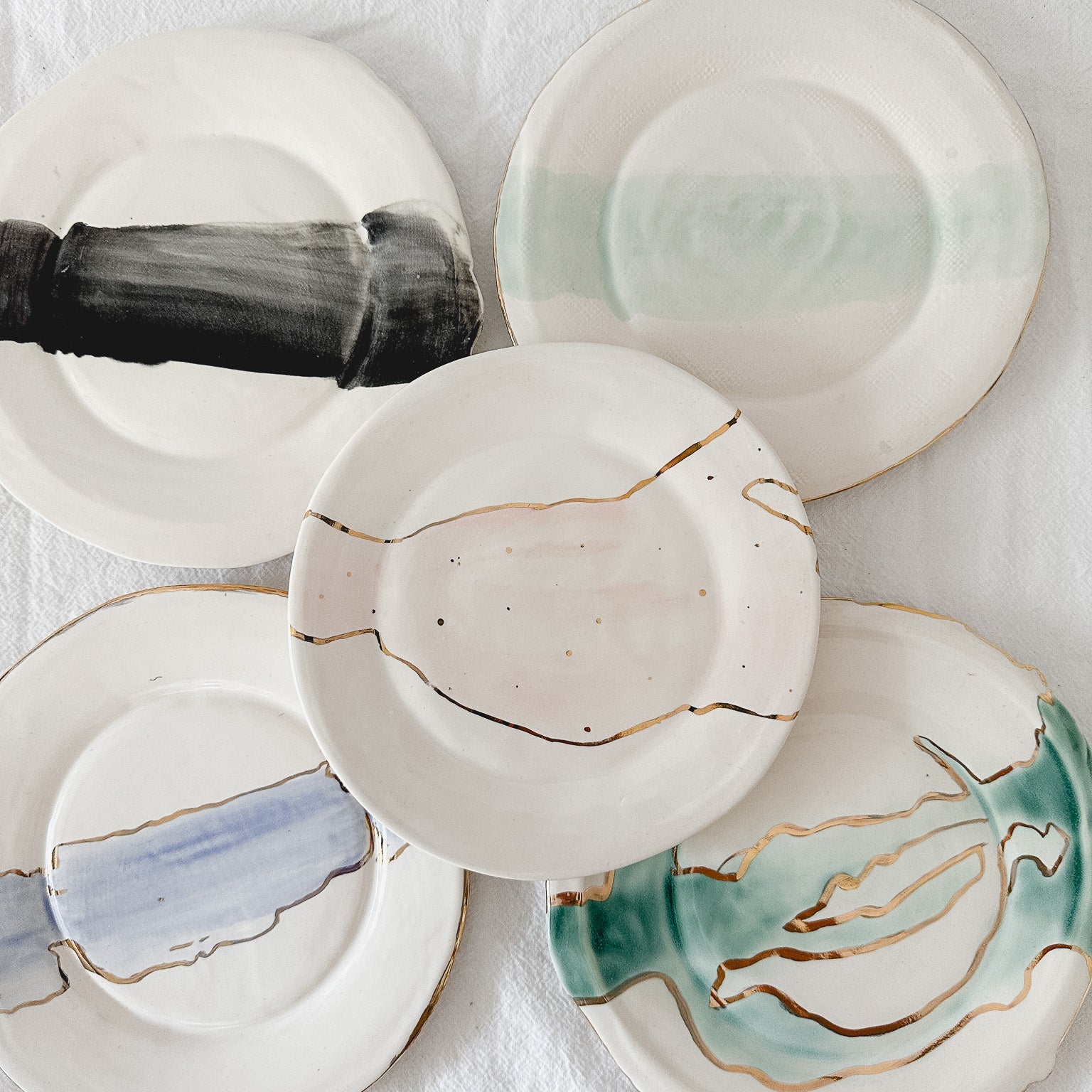 Handmade ceramic salad and dessert dishes with a watercolor glaze and real 22k gold luster line, seconds-sale pieces from Muddy Heart