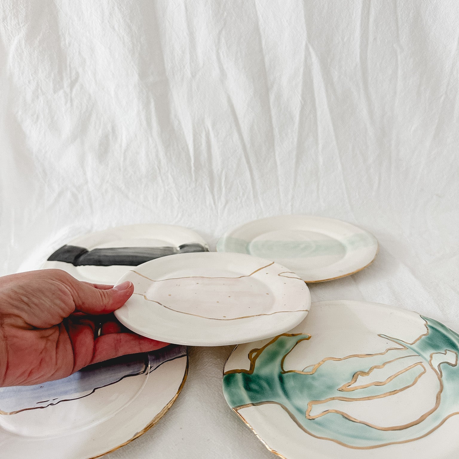 Handmade ceramic salad and dessert dishes with a watercolor glaze and real 22k gold luster line, seconds-sale pieces from Muddy Heart