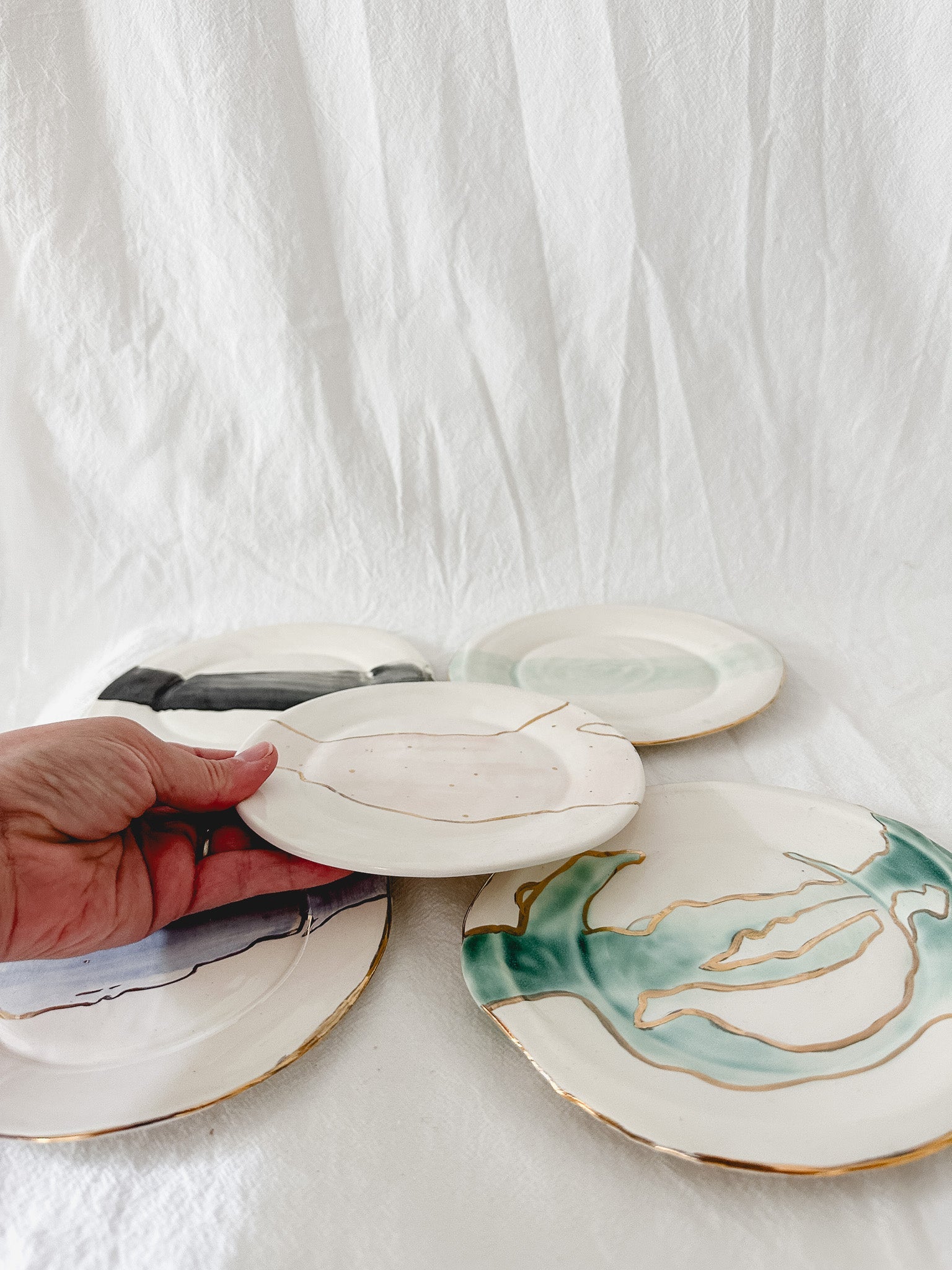 Handmade ceramic salad and dessert dishes with a watercolor glaze and real 22k gold luster line, seconds-sale pieces from Muddy Heart