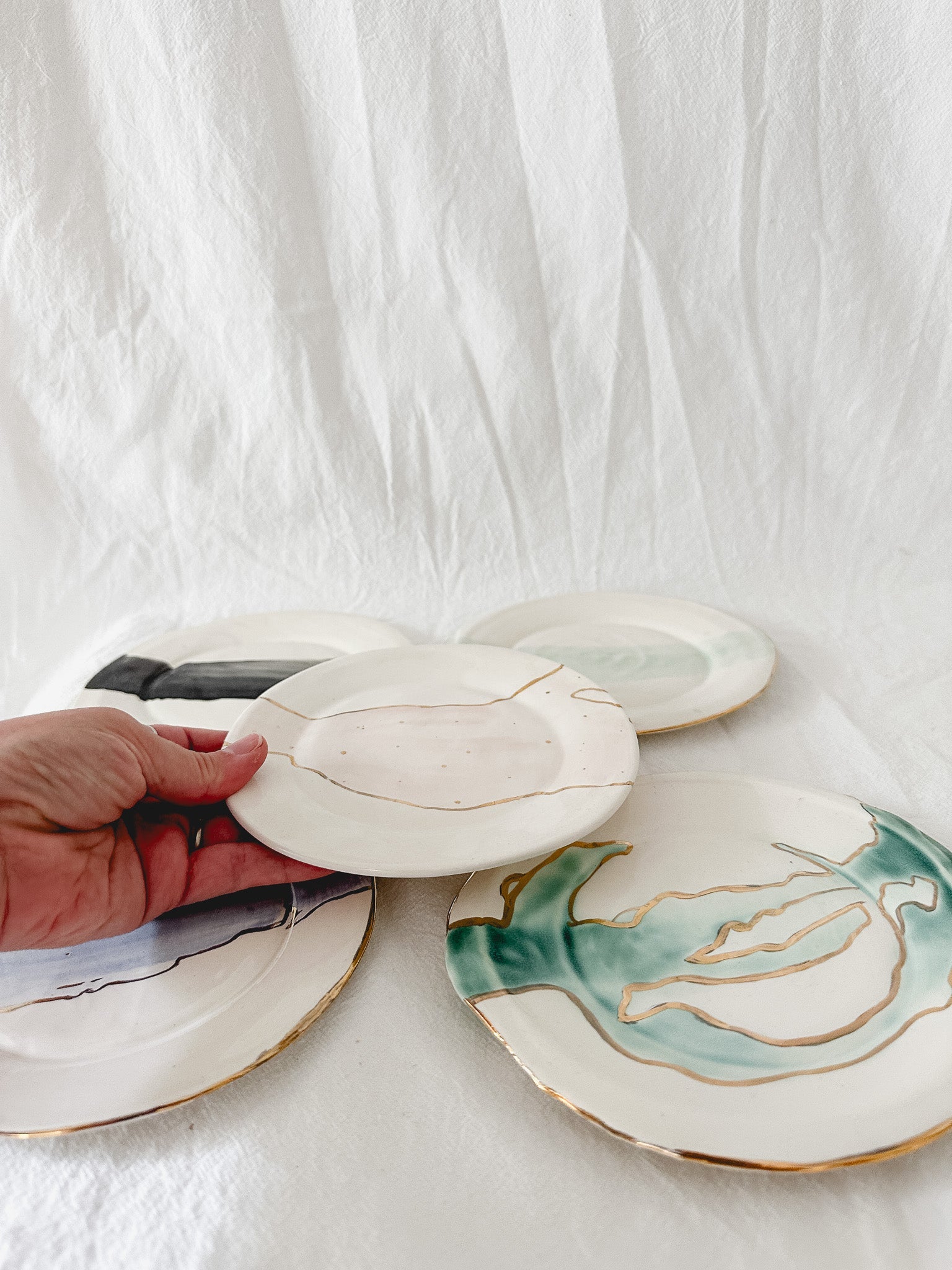 Handmade ceramic salad and dessert dishes with a watercolor glaze and real 22k gold luster line, seconds-sale pieces from Muddy Heart