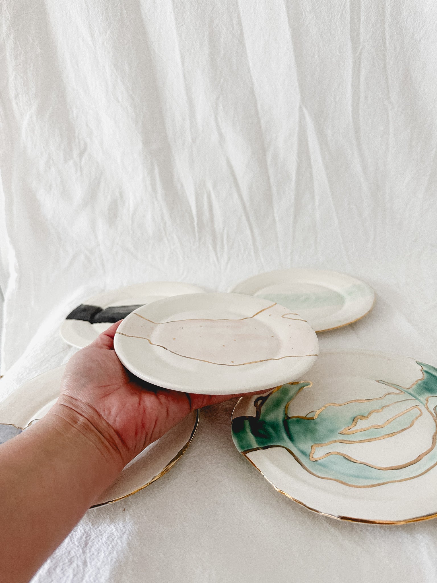 Handmade ceramic salad and dessert dishes with a watercolor glaze and real 22k gold luster line, seconds-sale pieces from Muddy Heart