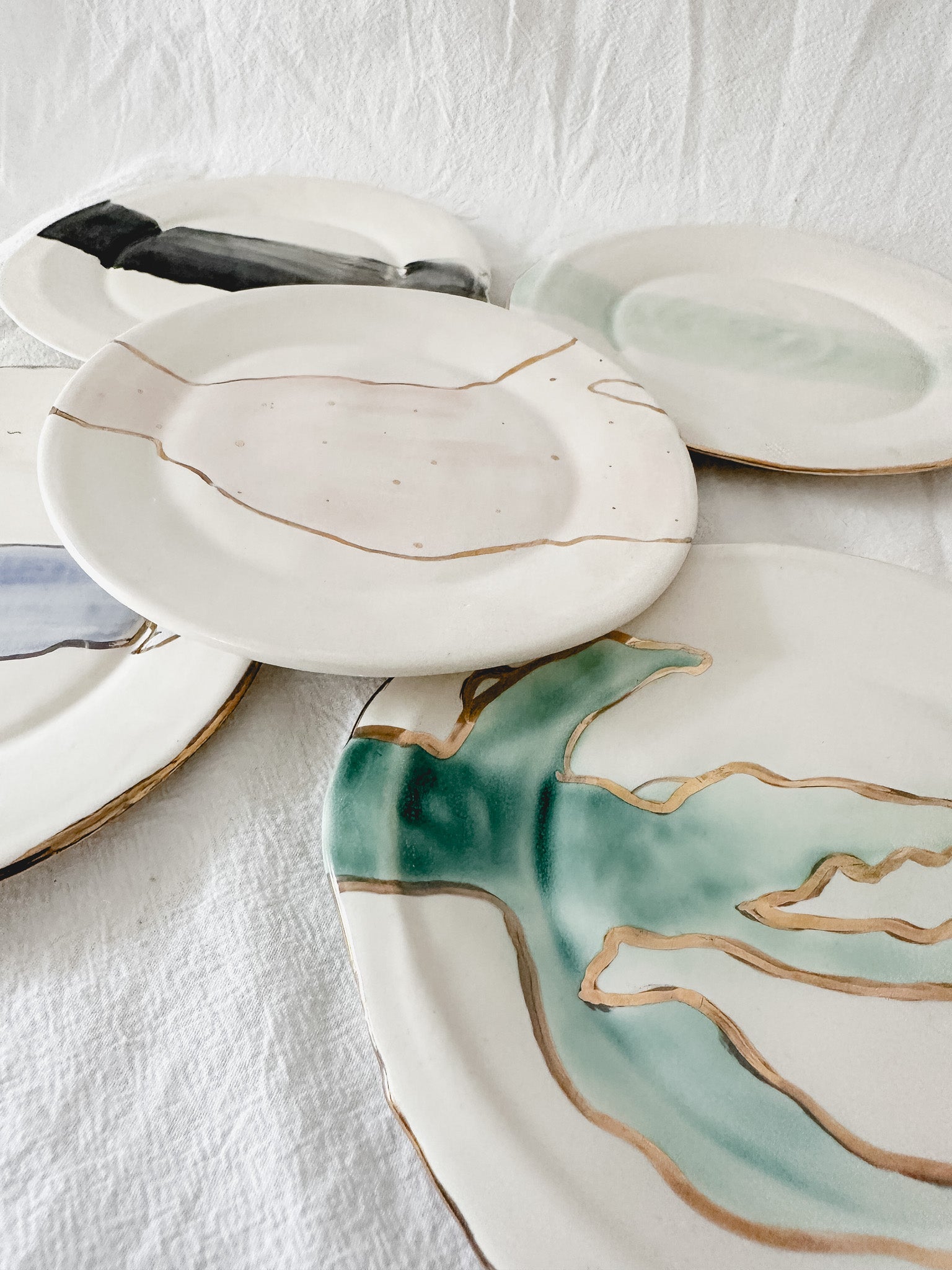Handmade ceramic salad and dessert dishes with a watercolor glaze and real 22k gold luster line, seconds-sale pieces from Muddy Heart
