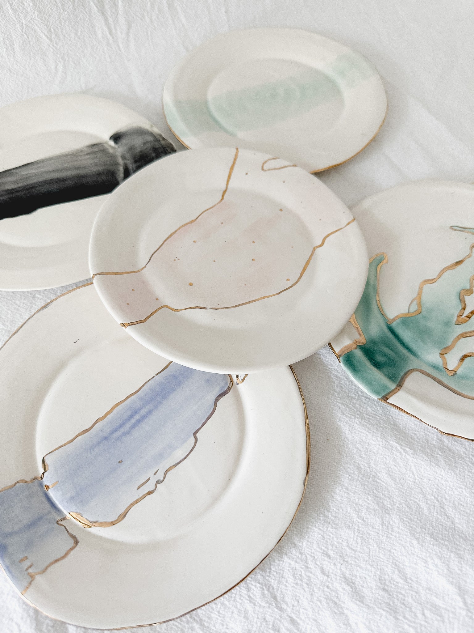 Handmade ceramic salad and dessert dishes with a watercolor glaze and real 22k gold luster line, seconds-sale pieces from Muddy Heart