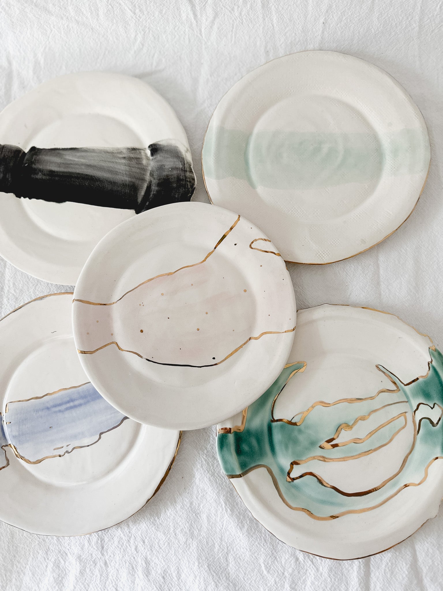 Handmade ceramic salad and dessert dishes with a watercolor glaze and real 22k gold luster line, seconds-sale pieces from Muddy Heart