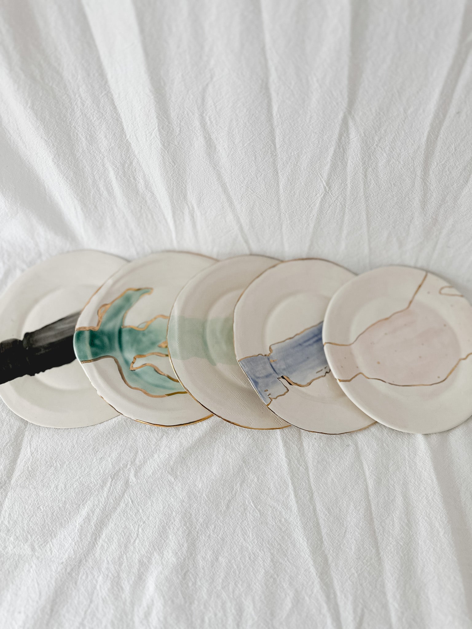 Handmade ceramic salad and dessert dishes with a watercolor glaze and real 22k gold luster line, seconds-sale pieces from Muddy Heart