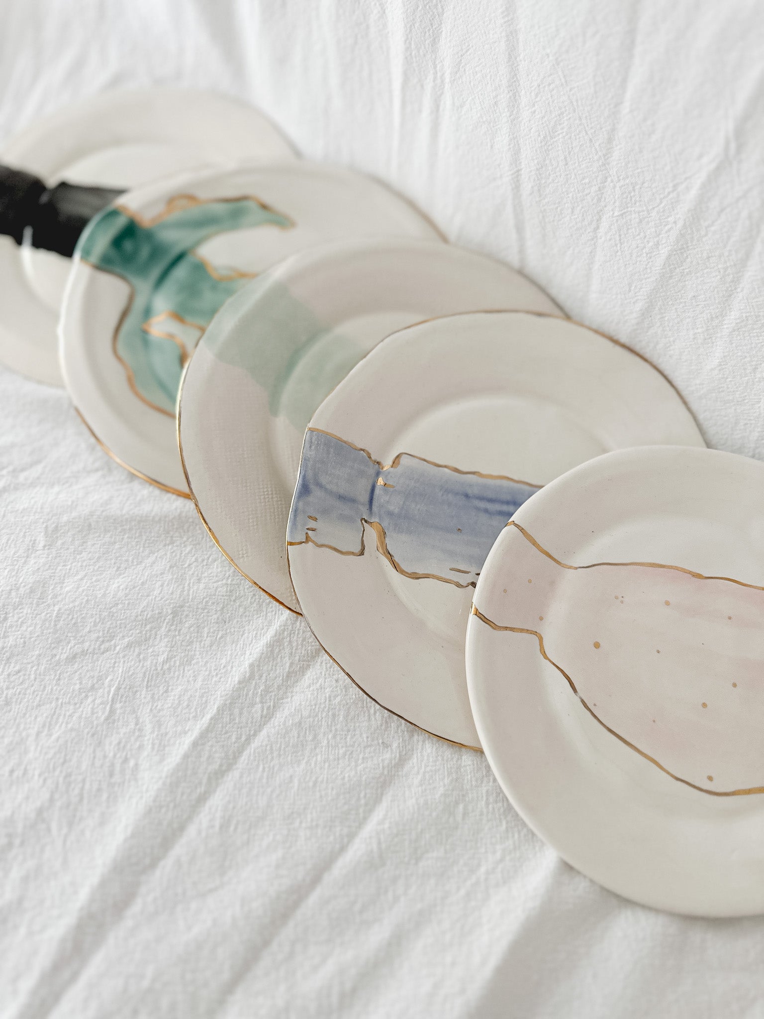 Handmade ceramic salad and dessert dishes with a watercolor glaze and real 22k gold luster line, seconds-sale pieces from Muddy Heart