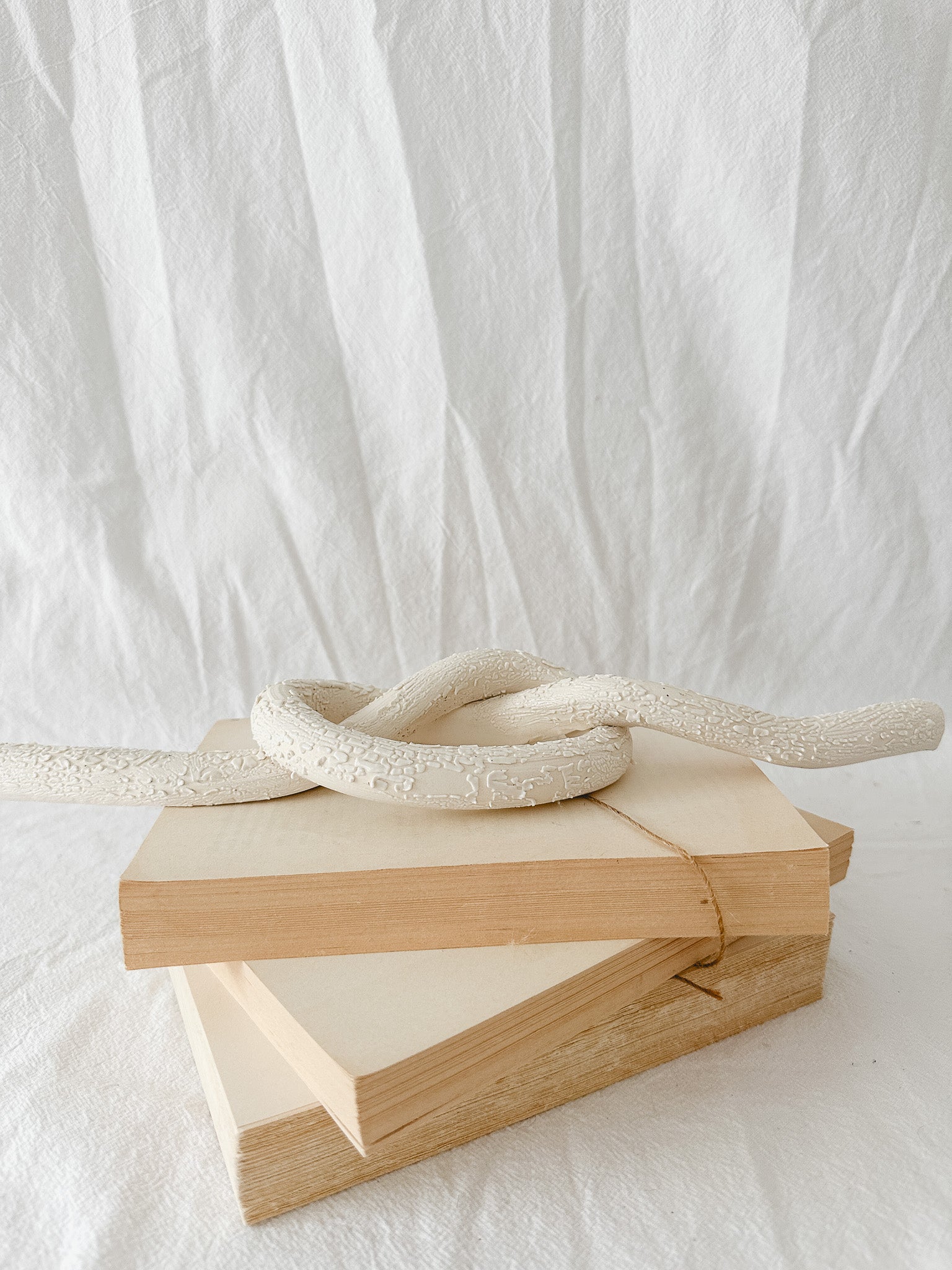 Handmade ceramic love knot decor object in textured white glaze, 12 inches long, one-of-a-kind piece from Muddy Heart