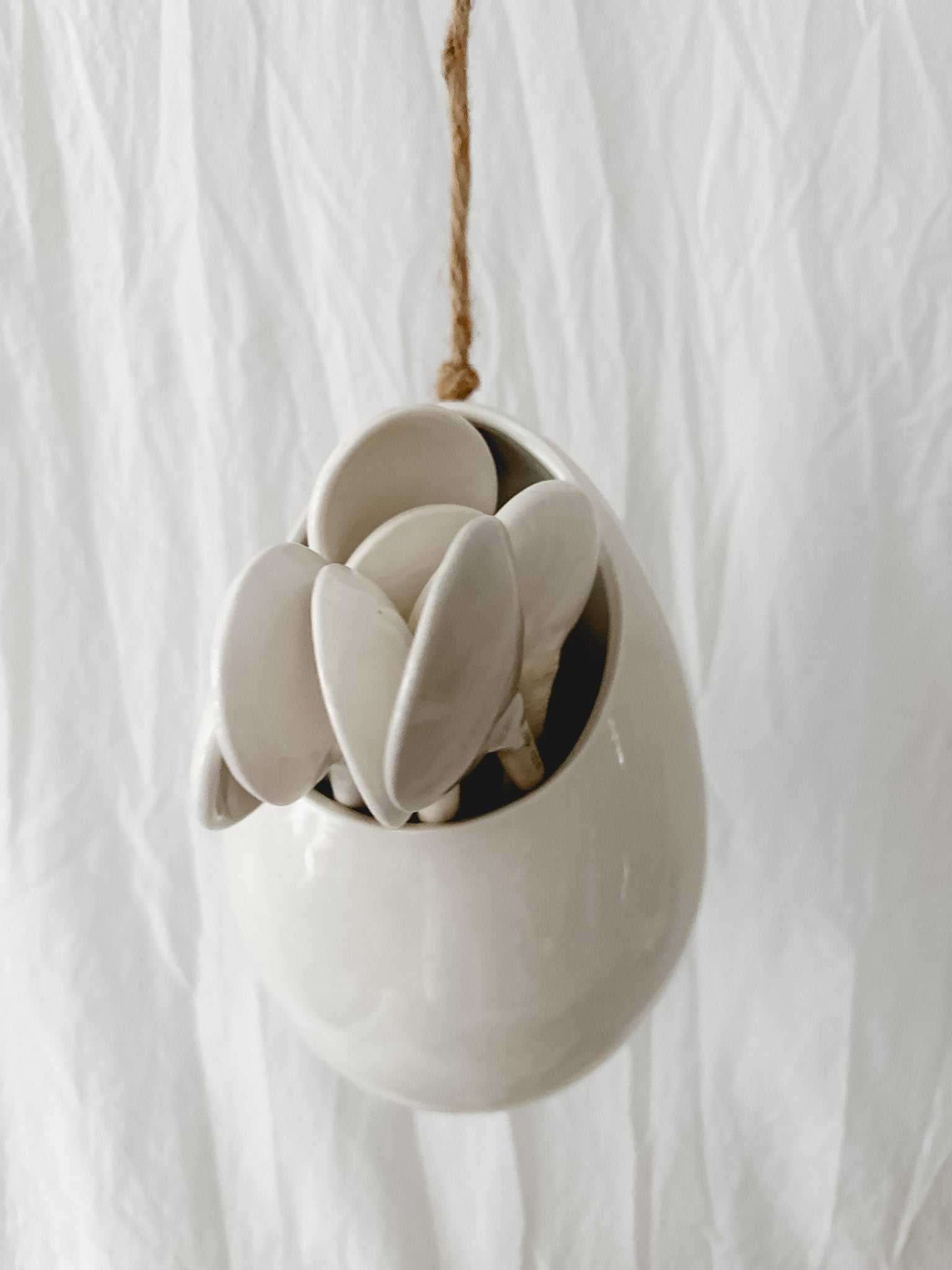 Handmade gloss white ceramic pod-shaped hanging vessel on an 18-inch rope, for flowers or trailing plants, seconds-sale piece from Muddy Heart