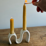 Handmade ceramic wiggle candelabra with organic free-form curves holding two taper candles.