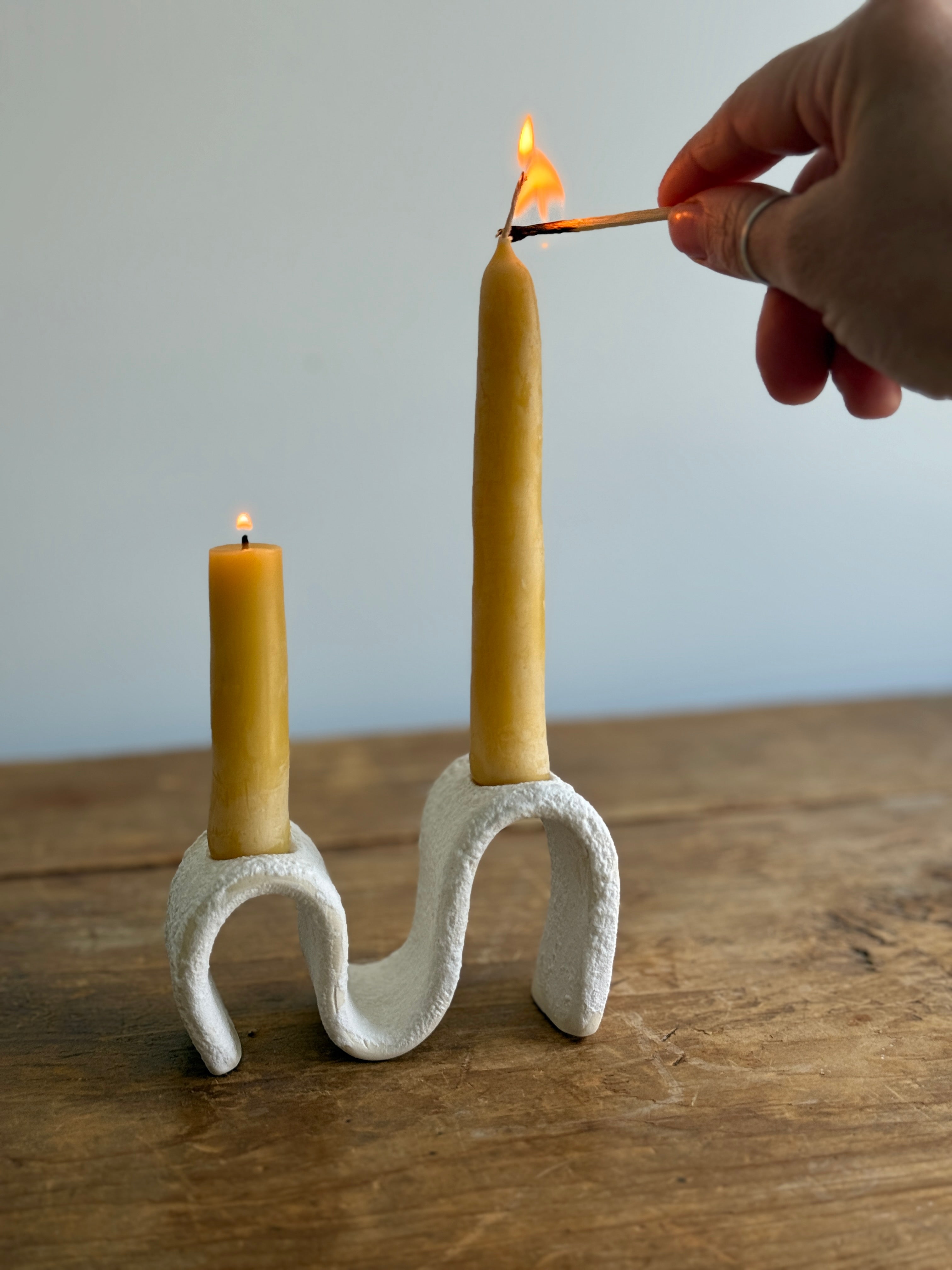Handmade ceramic wiggle candelabra with organic free-form curves holding two taper candles.