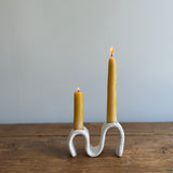 Handmade ceramic wiggle candelabra with organic free-form curves holding two taper candles.