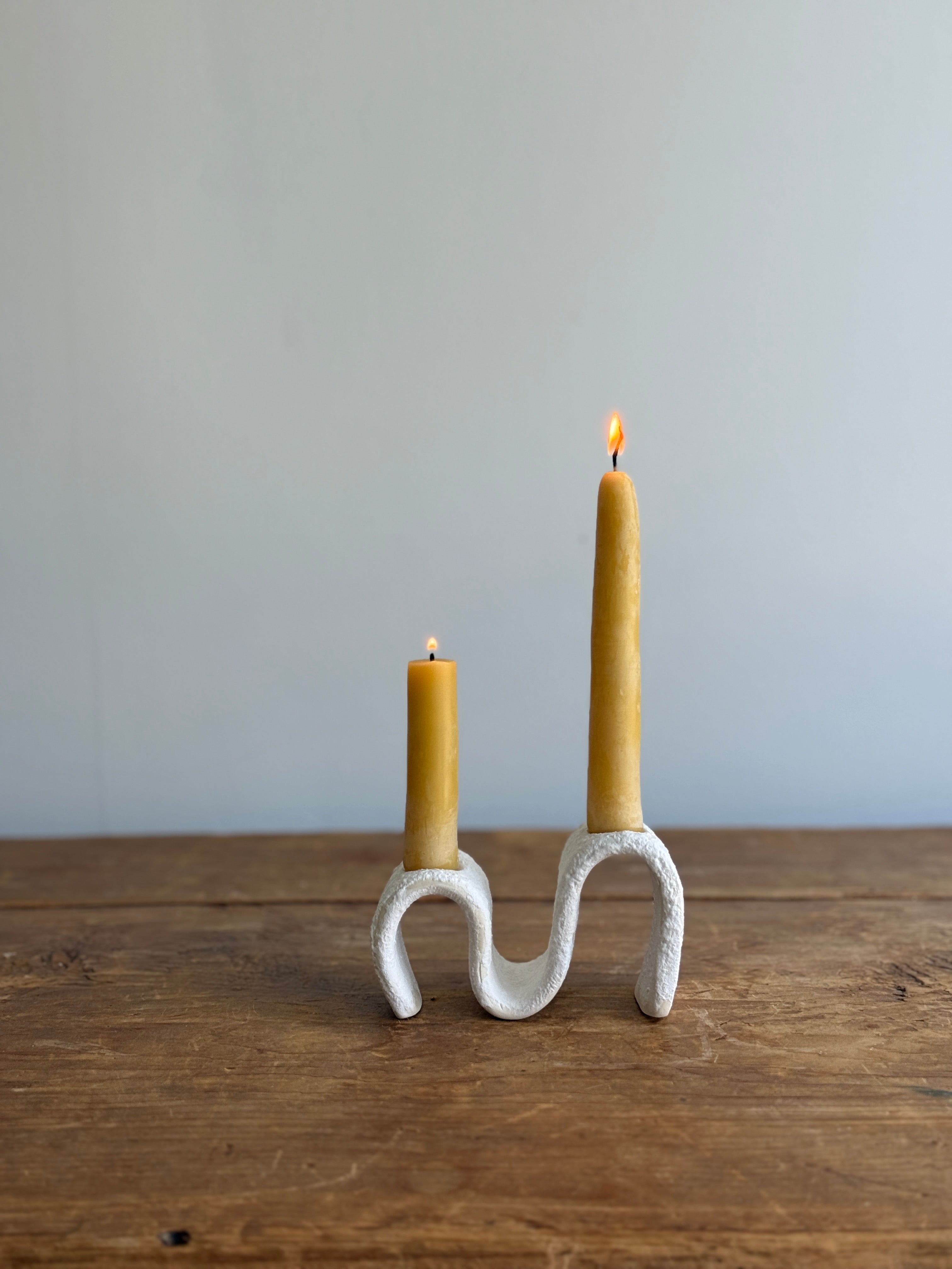 Handmade ceramic wiggle candelabra with organic free-form curves holding two taper candles.