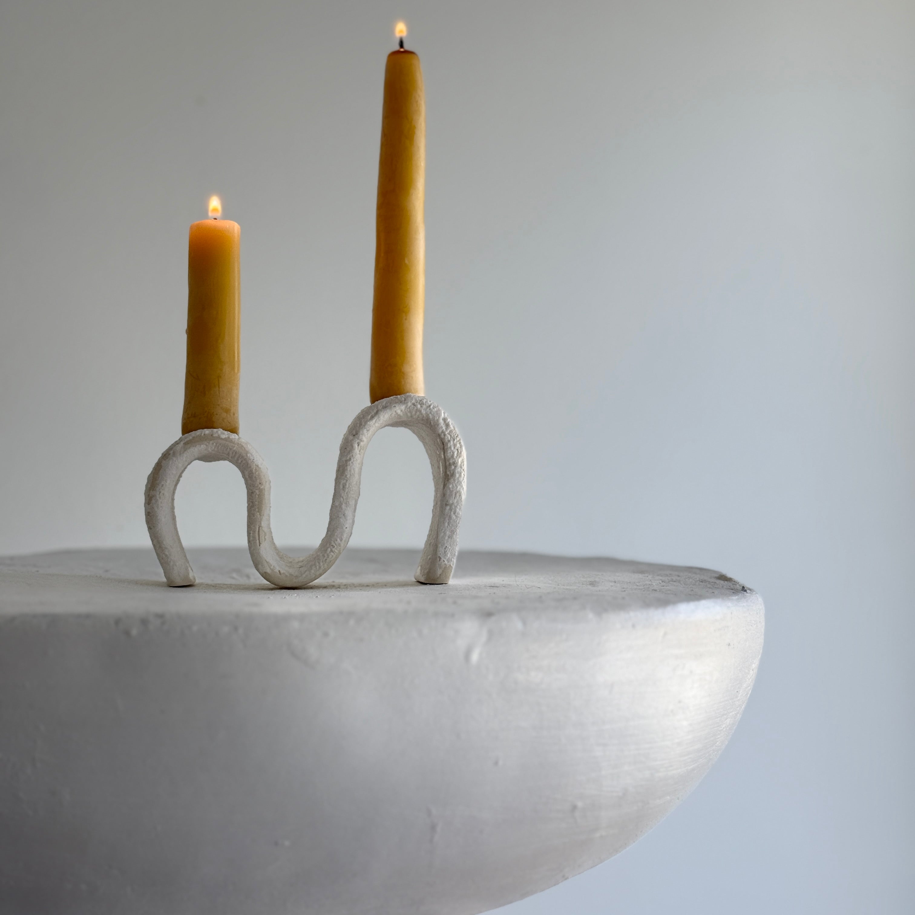 Handmade ceramic wiggle candelabra with organic free-form curves holding two taper candles.