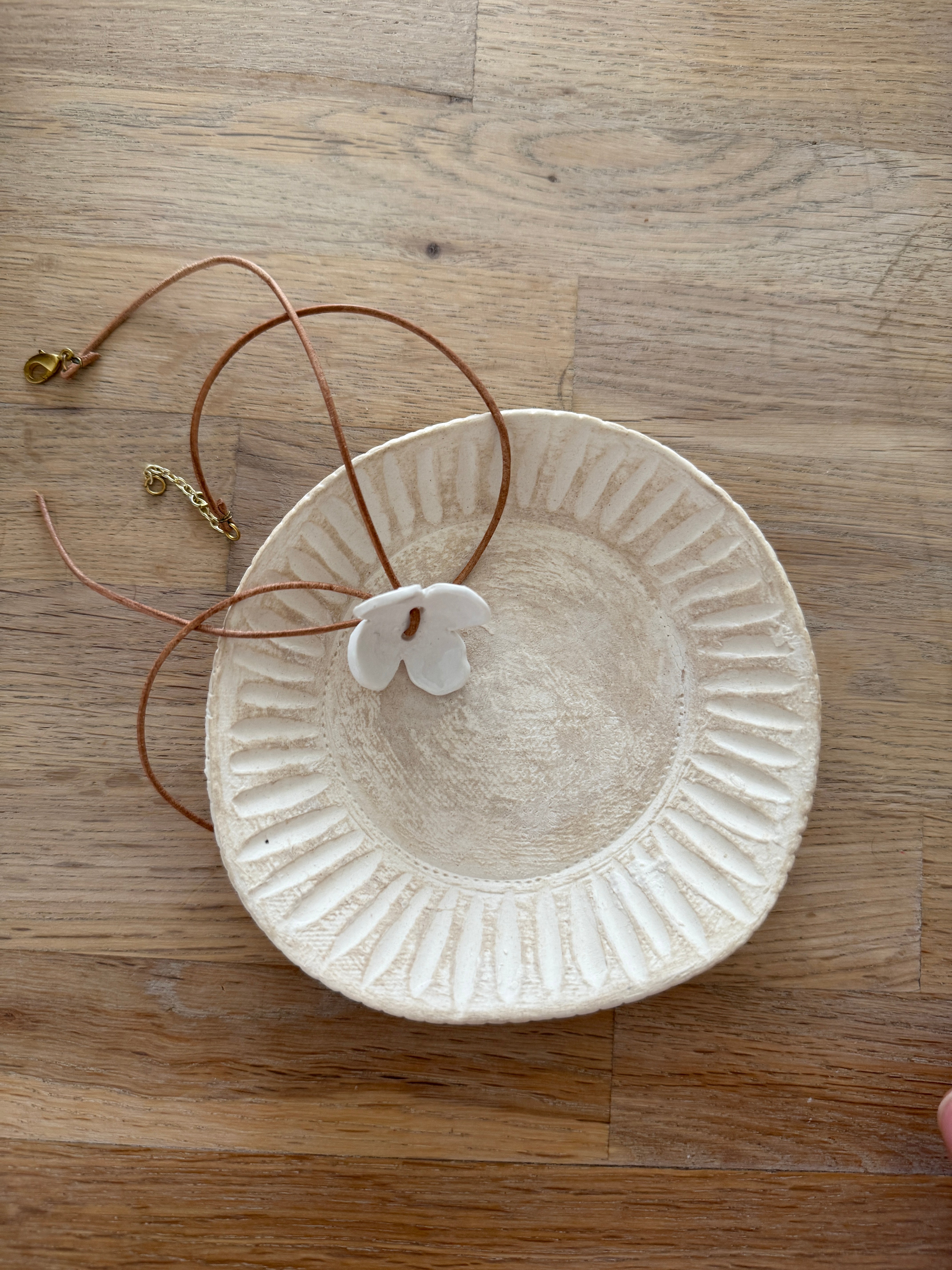 Handmade porcelain dogwood flower choker necklace on an adjustable leather cord.