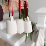 Handmade ceramic holiday bell ornament with a white eggshell finish and red velvet ribbon