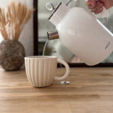 Handmade ceramic coffee mug with hand-carved vertical column lines and a glossy white interior.