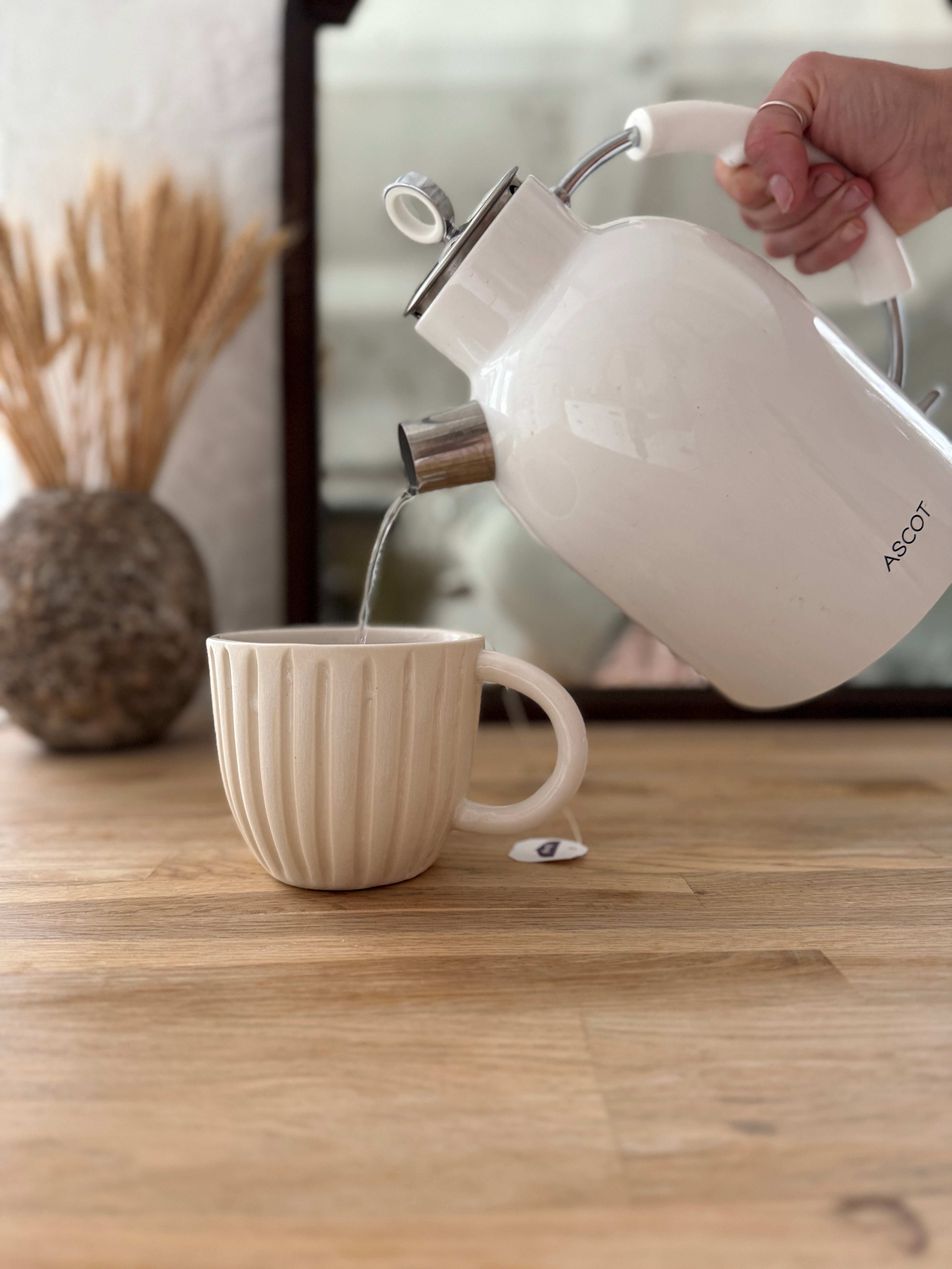 Handmade ceramic coffee mug with hand-carved vertical column lines and a glossy white interior.
