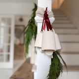 Handmade ceramic holiday bell ornament with a white eggshell finish and red velvet ribbon