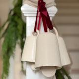 Handmade ceramic holiday bell ornament with a white eggshell finish and red velvet ribbon